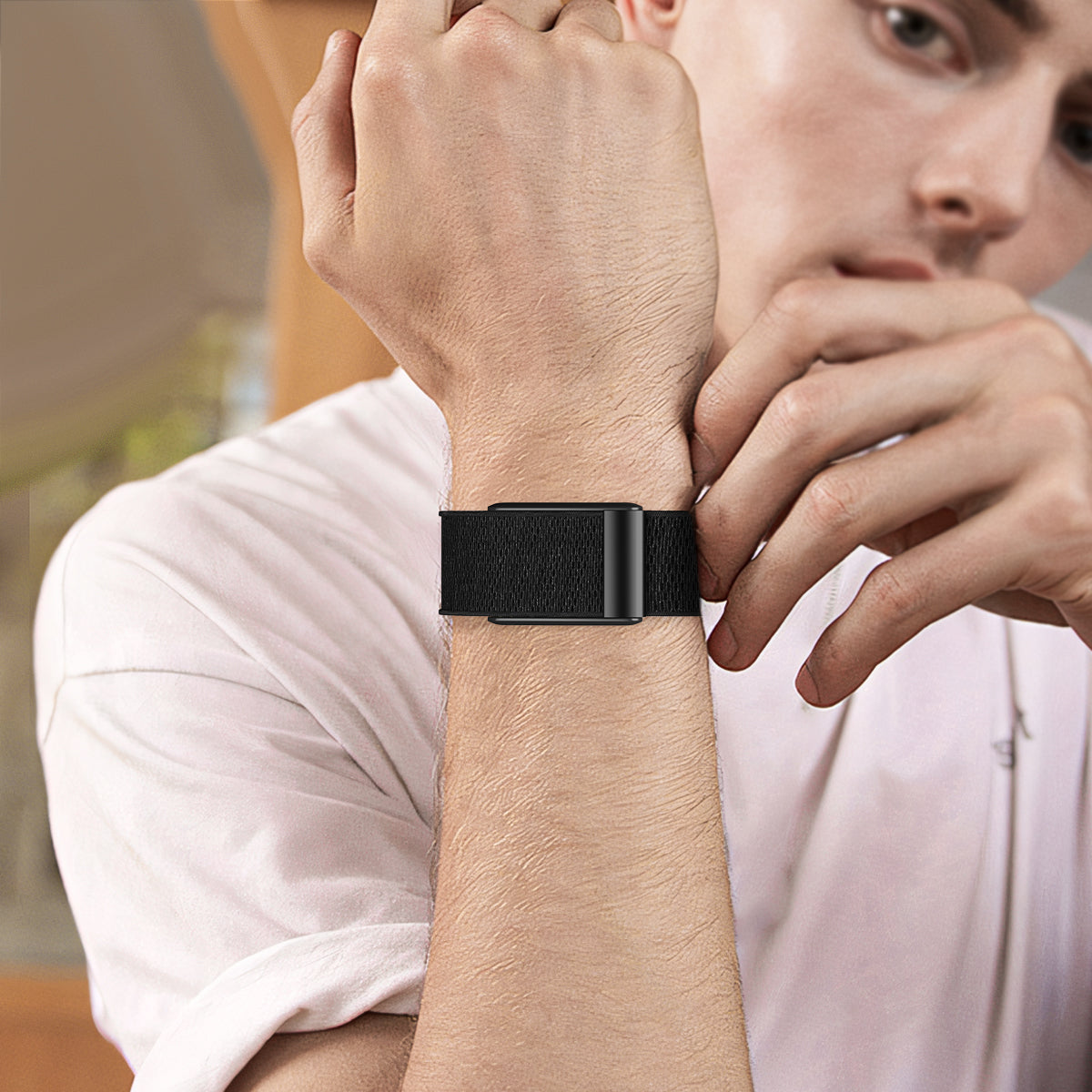 Man wearing black woven loop band fitness tracker on wrist with white shirt
