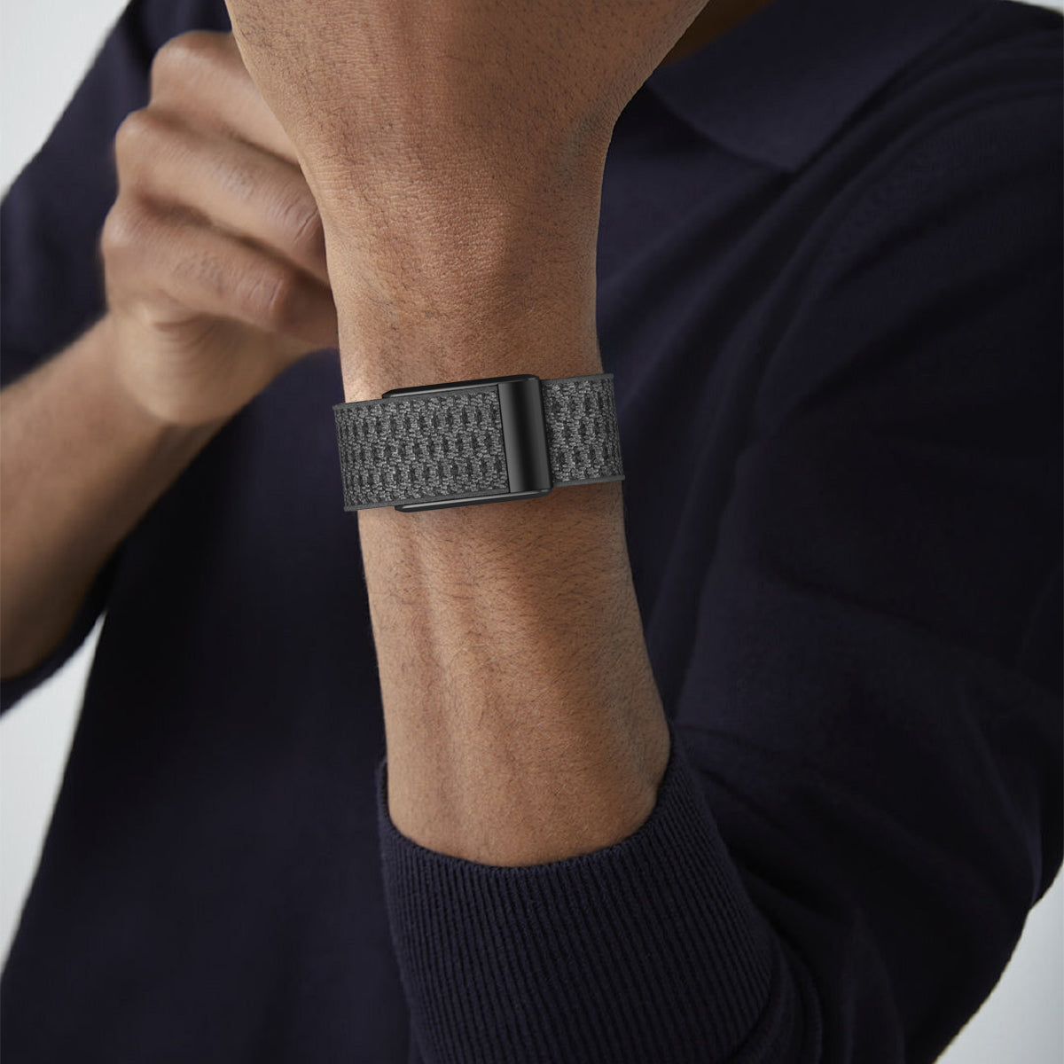 Gray knit fabric watch strap with black buckle closure on man's wrist wearing dark navy shirt