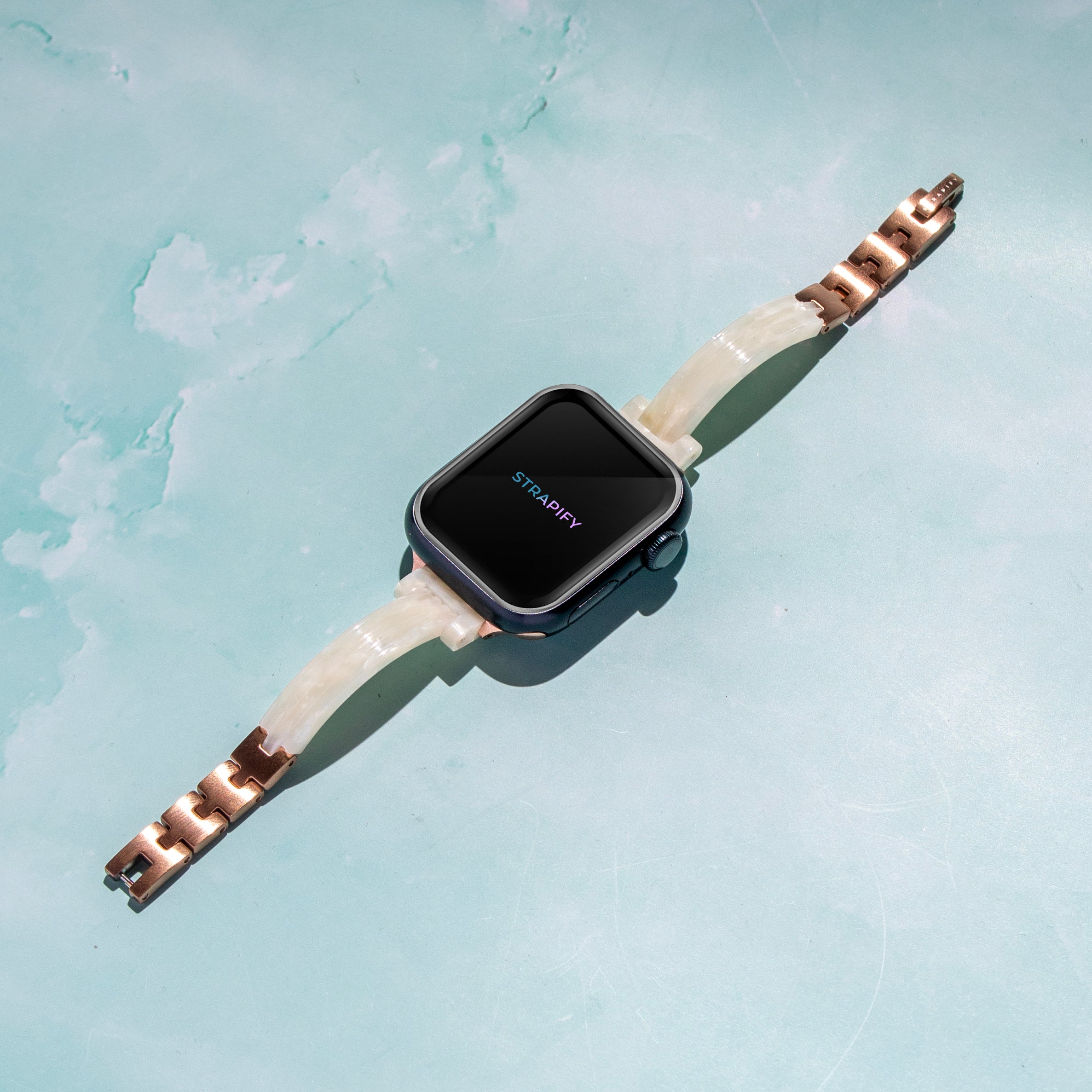 Strapify white pearl acetate bangle smartwatch band with rose gold hardware on turquoise background
