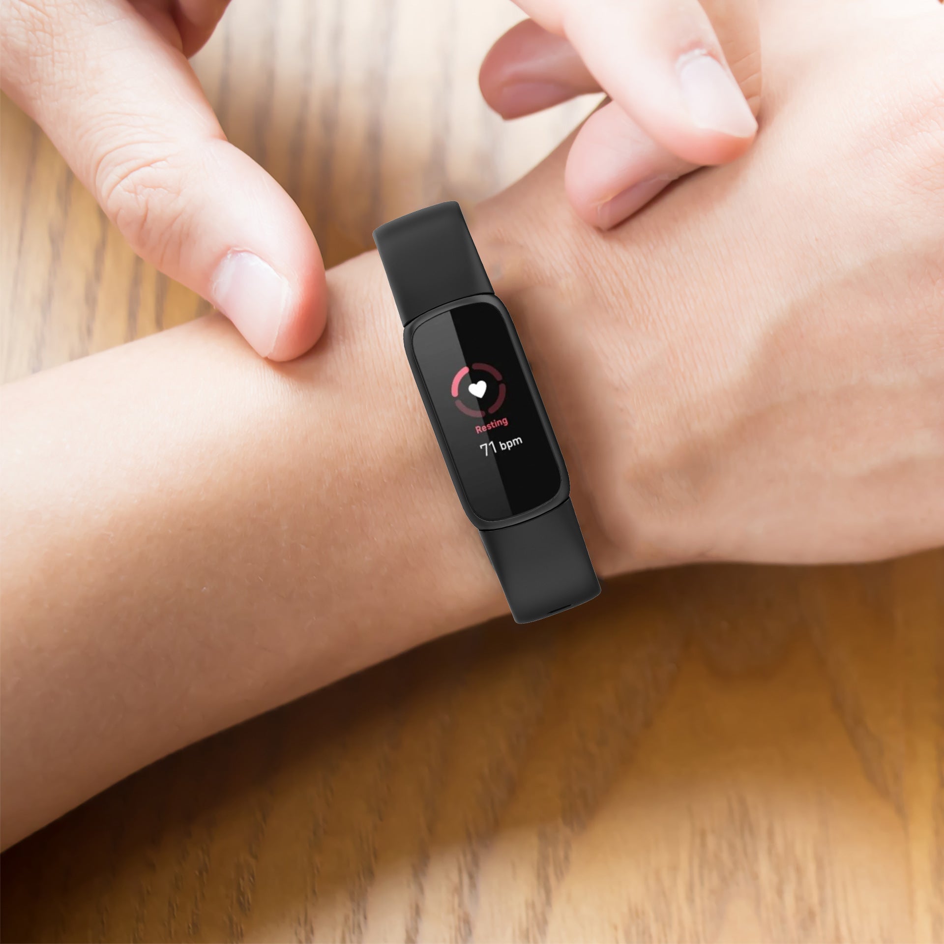 Black silicone fitness tracker displaying resting heart rate of 77 bpm on woman's wrist
