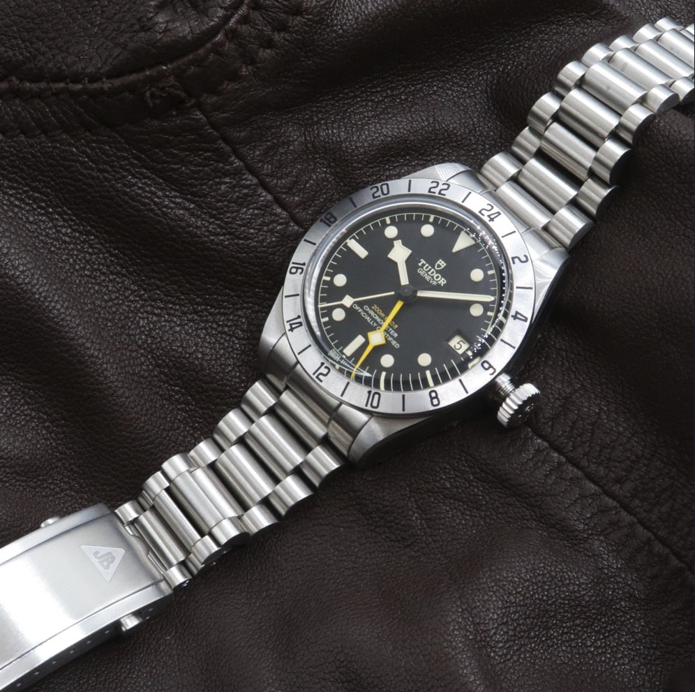 Tudor Black Bay Pro stainless steel dive watch with GMT bezel and Forstner President bracelet on black leather background