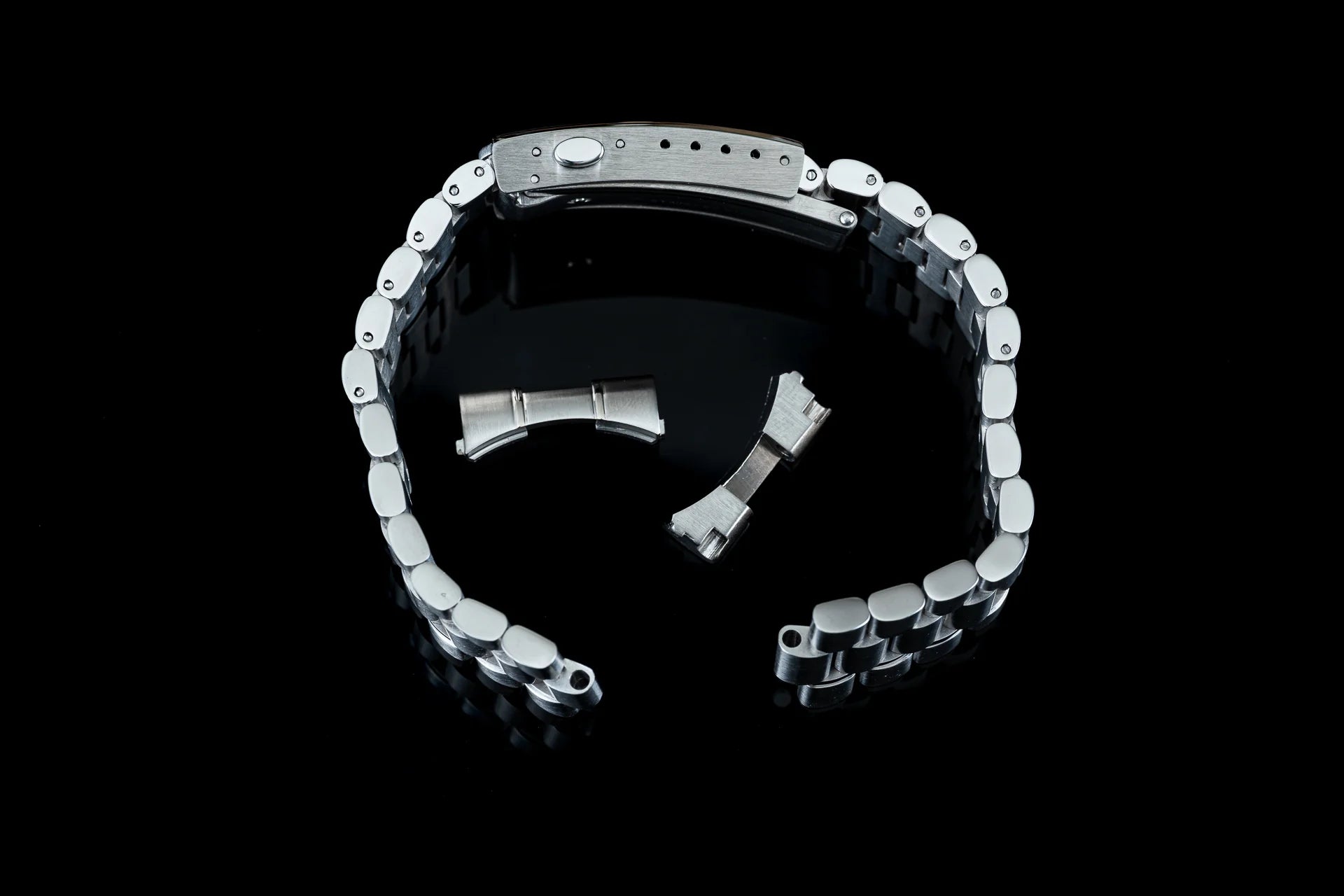 Two-tone stainless steel bracelet with silver links and black accents, featuring adjustment links and butterfly clasp for Speedmaster watch