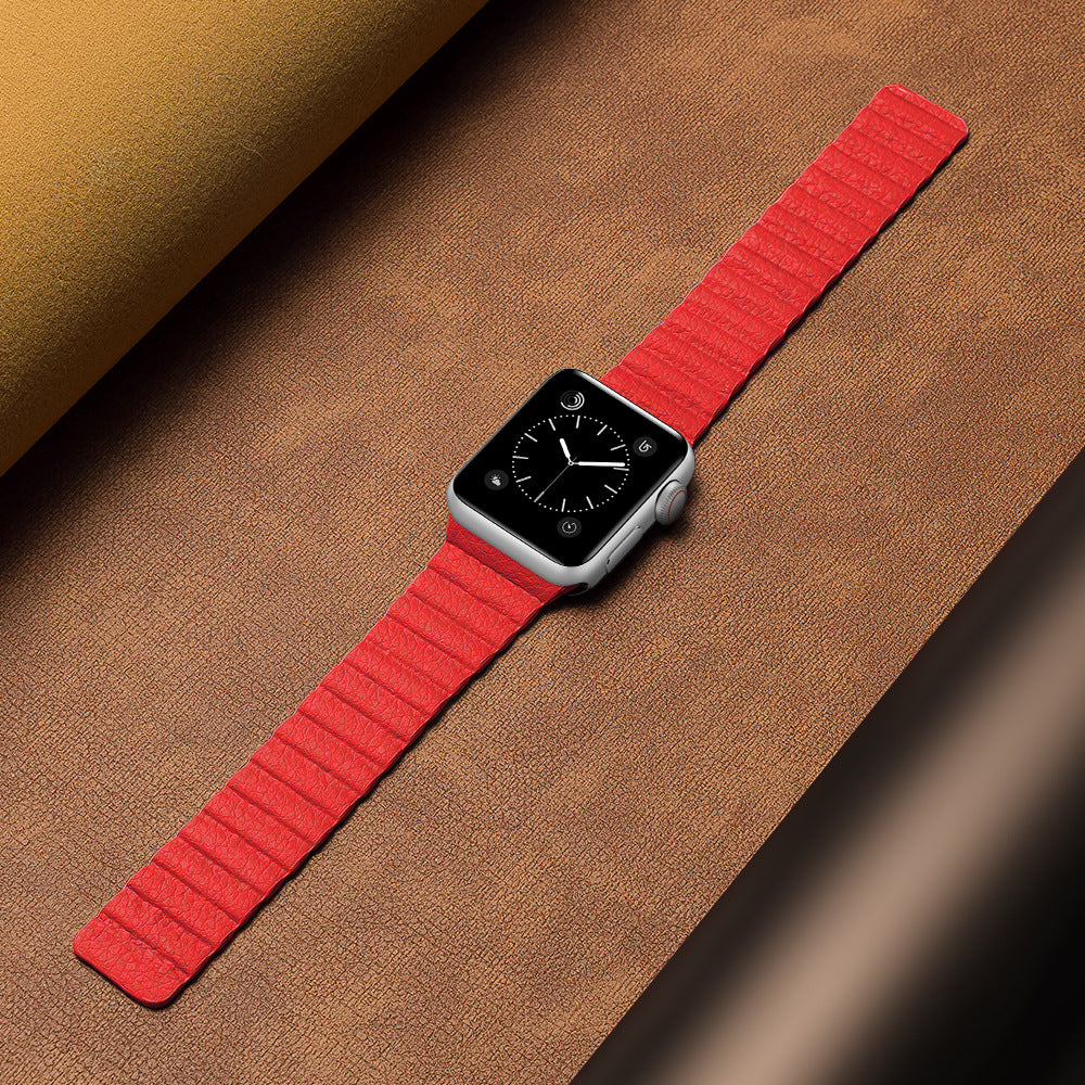 Apple Watch with red leather loop band on tan textured background, showing black watch face with time display