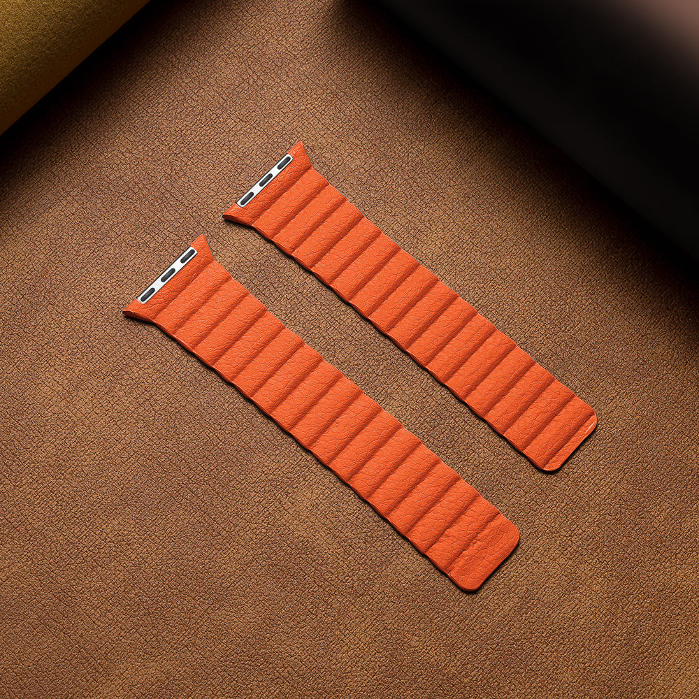 Orange leather loop apple watch bands with magnetic closure on tan fabric background