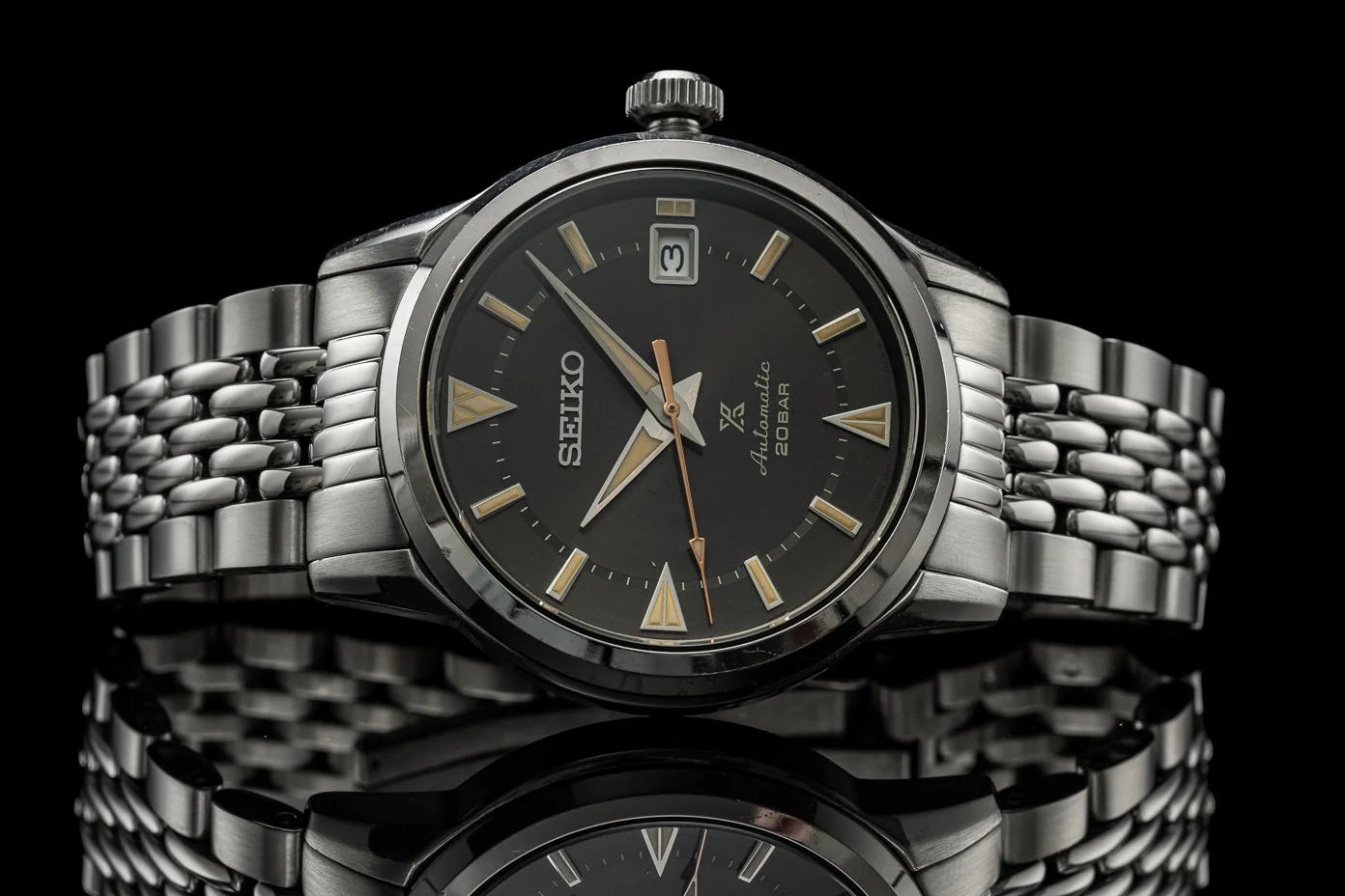 Seiko Alpinist automatic watch with black dial, gold hour markers, stainless steel beads of rice bracelet, and date window