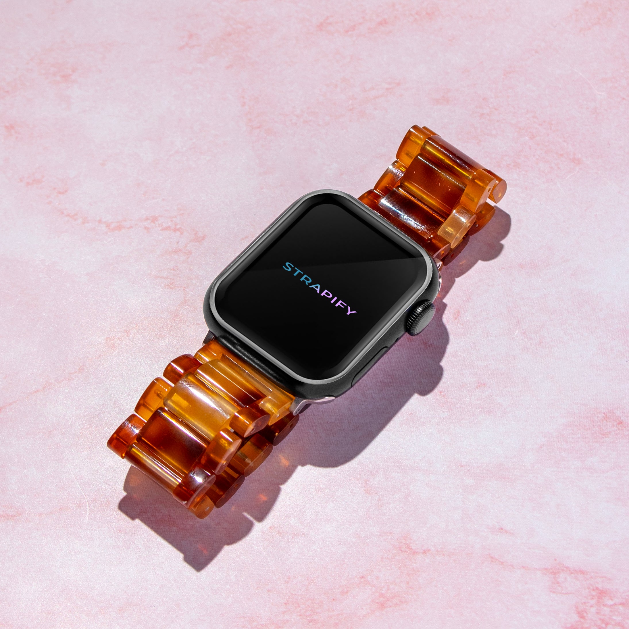Strapify tortoiseshell brown acetate smartwatch band on black square face watch against pink textured background