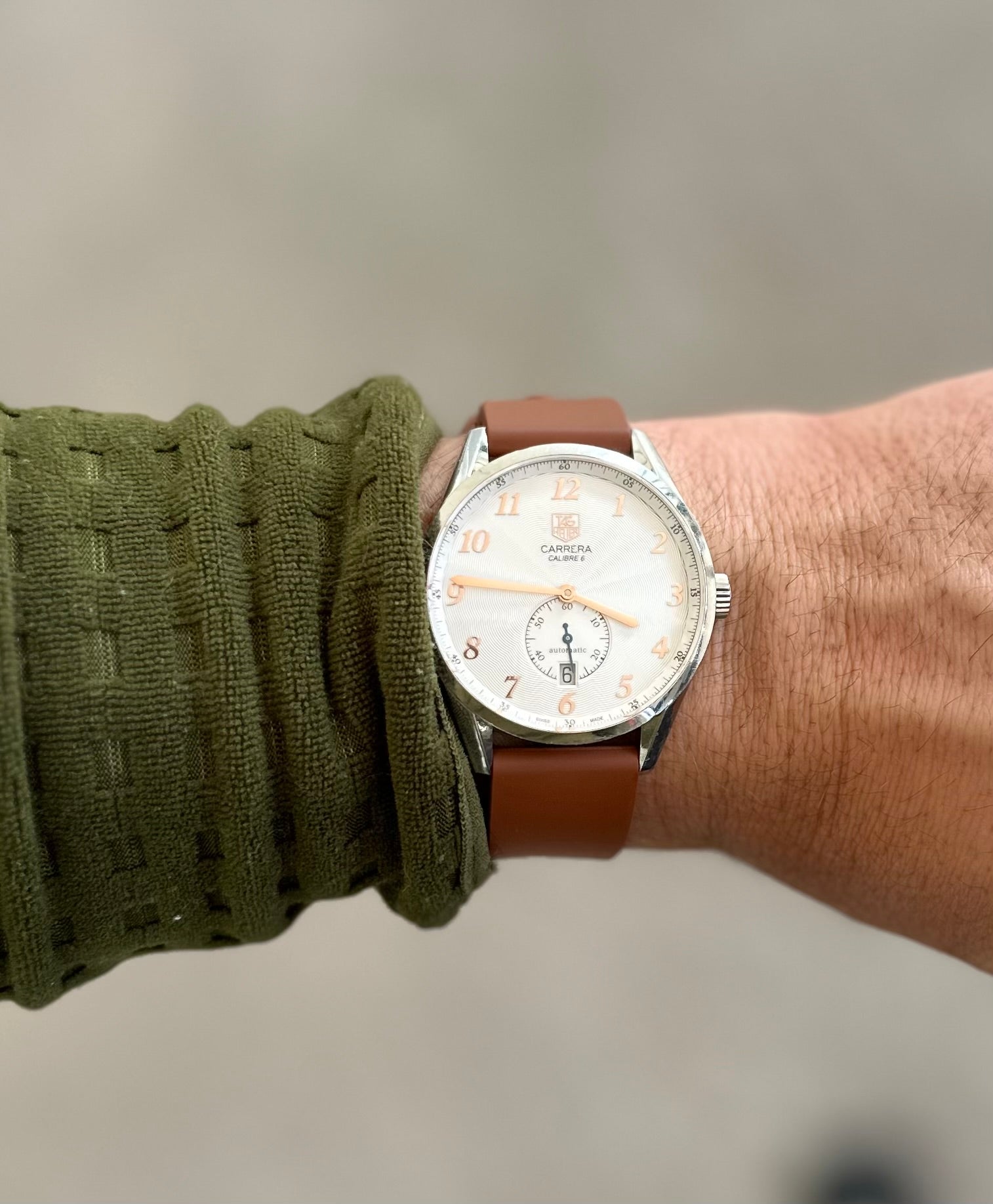 Carrera Calibre 6 watch with silver case, cream dial, brown leather strap worn on wrist with green sweater