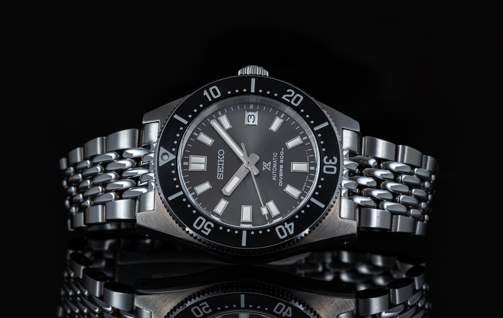 Seiko Prospex automatic diver's watch with stainless steel beads of rice bracelet and black dial on black background