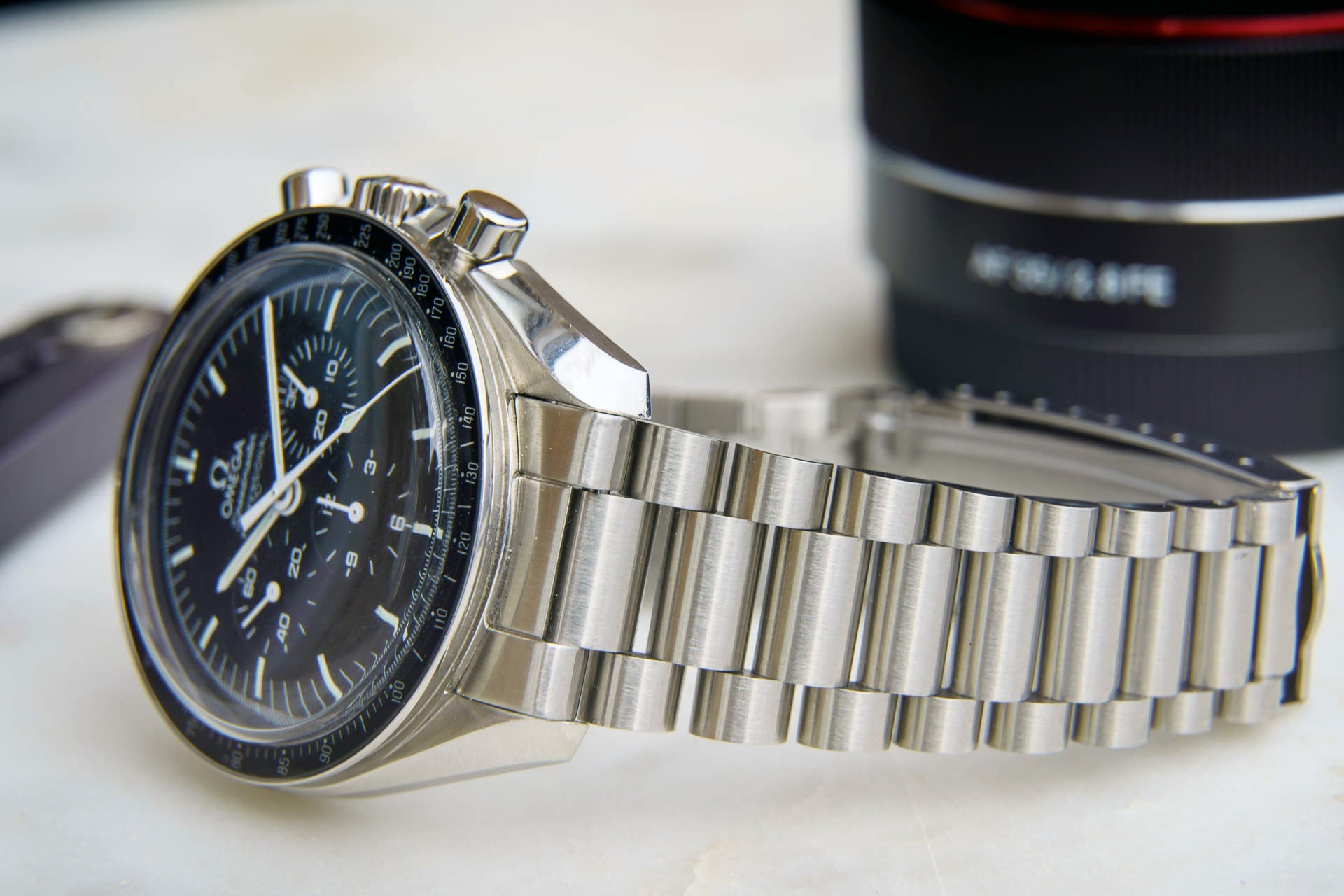Omega Speedmaster professional chronograph watch with black dial and stainless steel bracelet on white surface