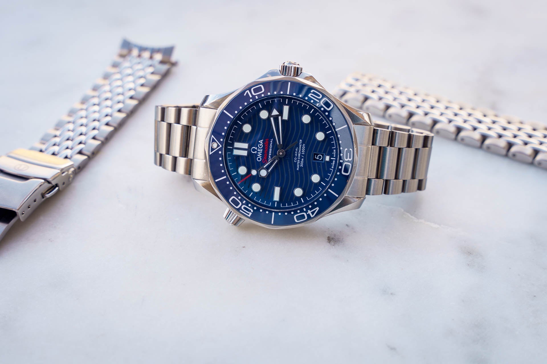 Omega Seamaster 300M dive watch with blue dial, stainless steel bracelet, displayed on marble surface