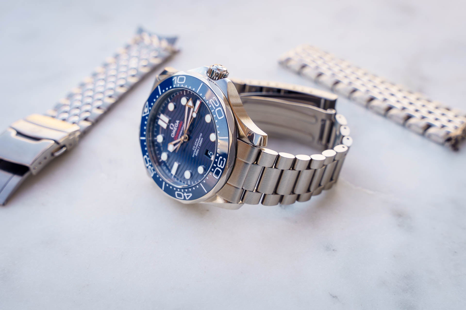 Stainless steel diving watch with blue dial and bezel, matching metal bracelet, professional timepiece on white background