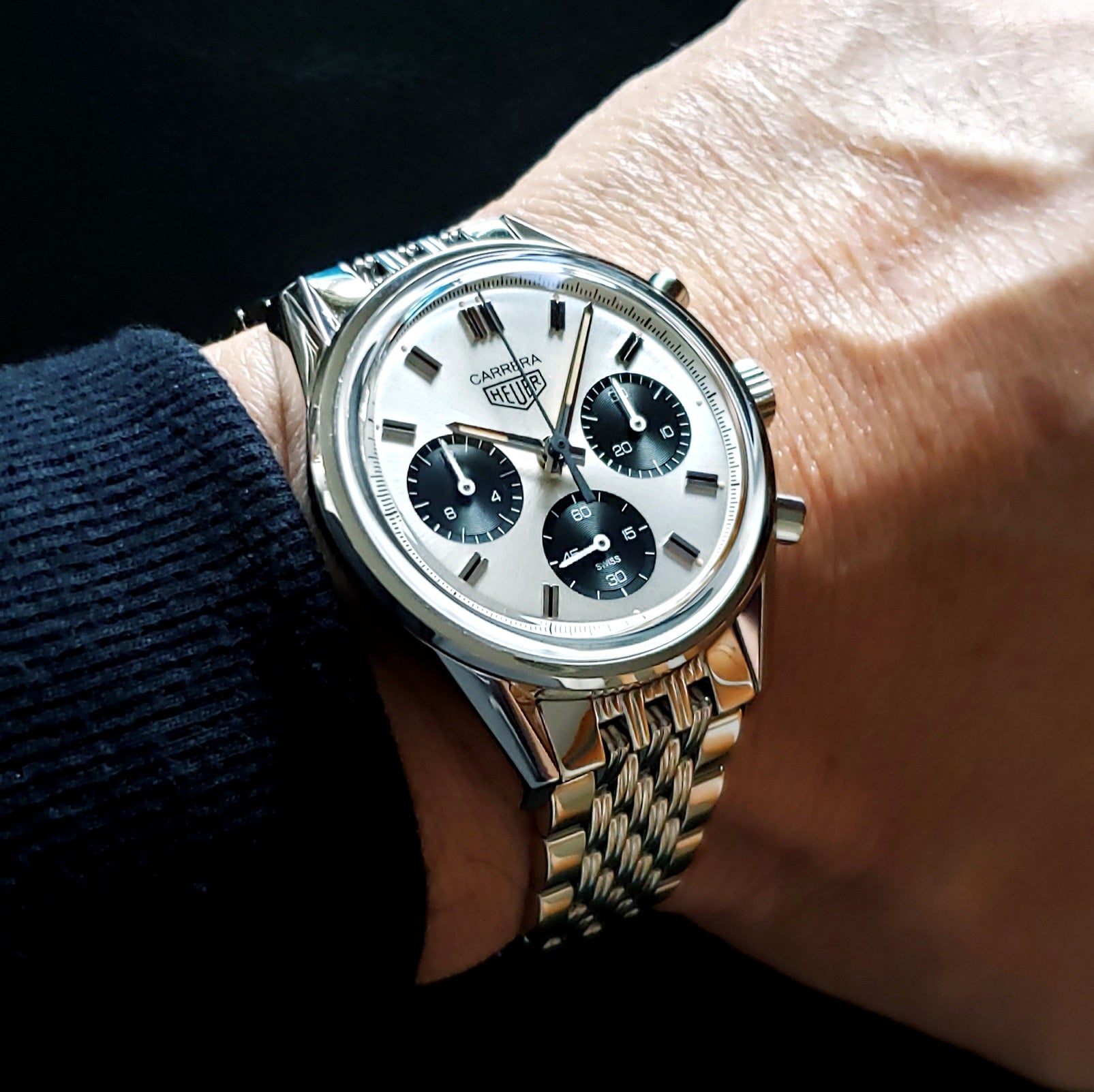 Tag Heuer Carrera chronograph watch with silver steel bracelet and white dial with black subdials worn on wrist