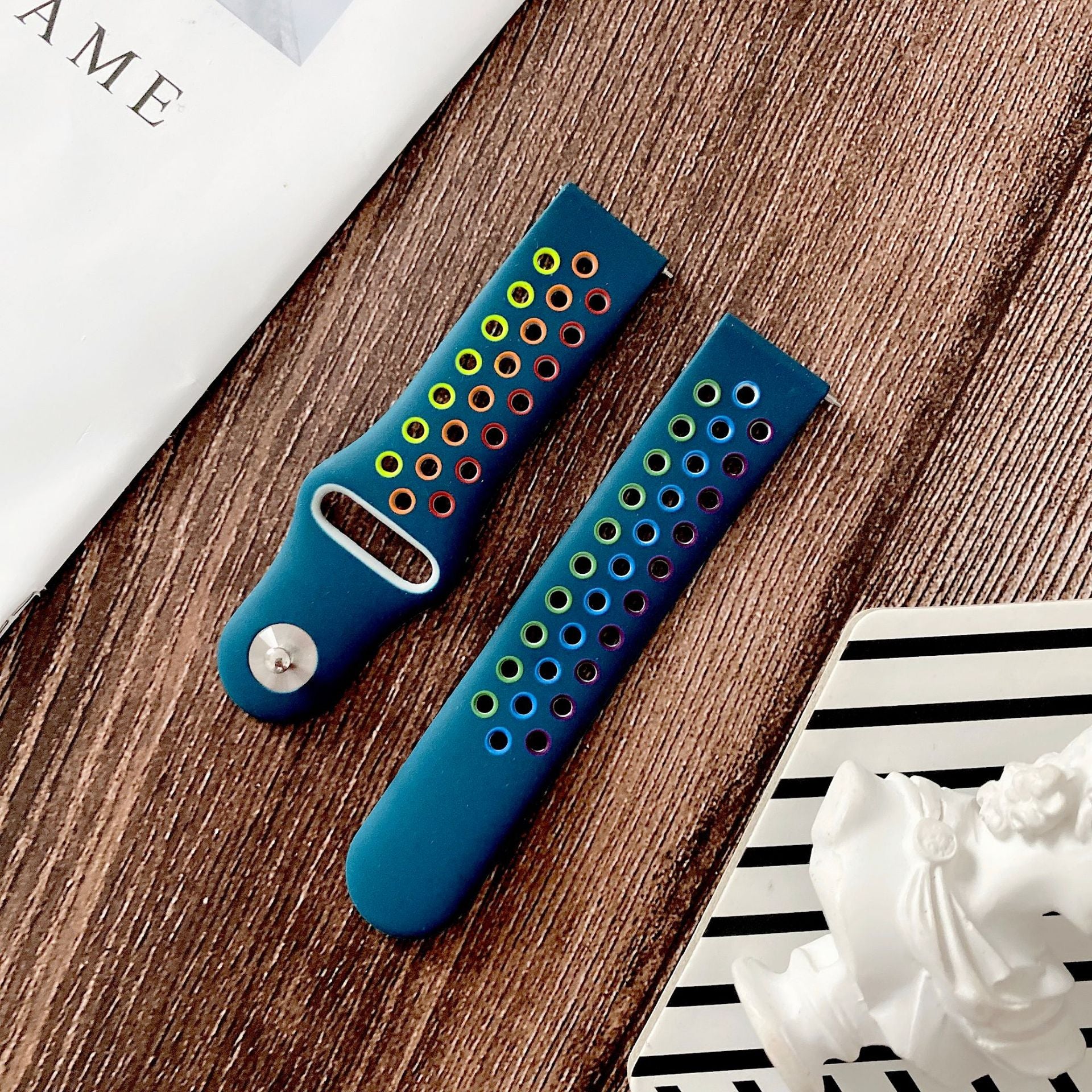 Blue silicone sport watch band with colorful rainbow vented holes and quick release connector on wood background