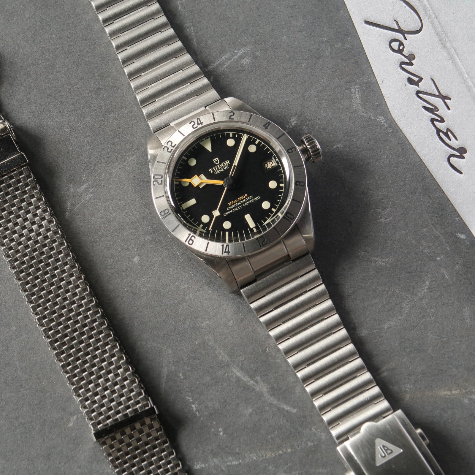 Tudor Black Bay Pro stainless steel dive watch with GMT bezel and barrel bracelet on gray background