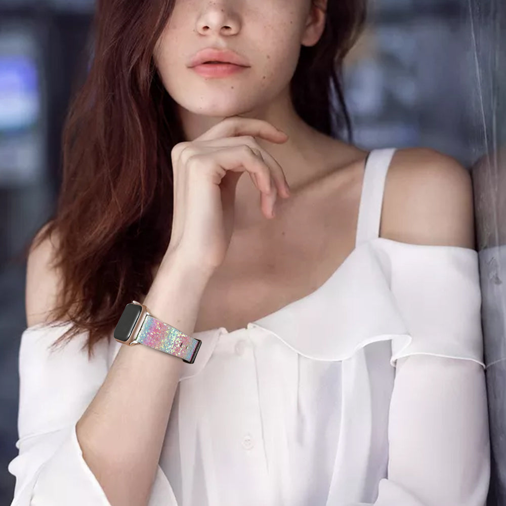 Woman wearing white off-shoulder top with colorful rainbow glitter Apple Watch band with gold hardware