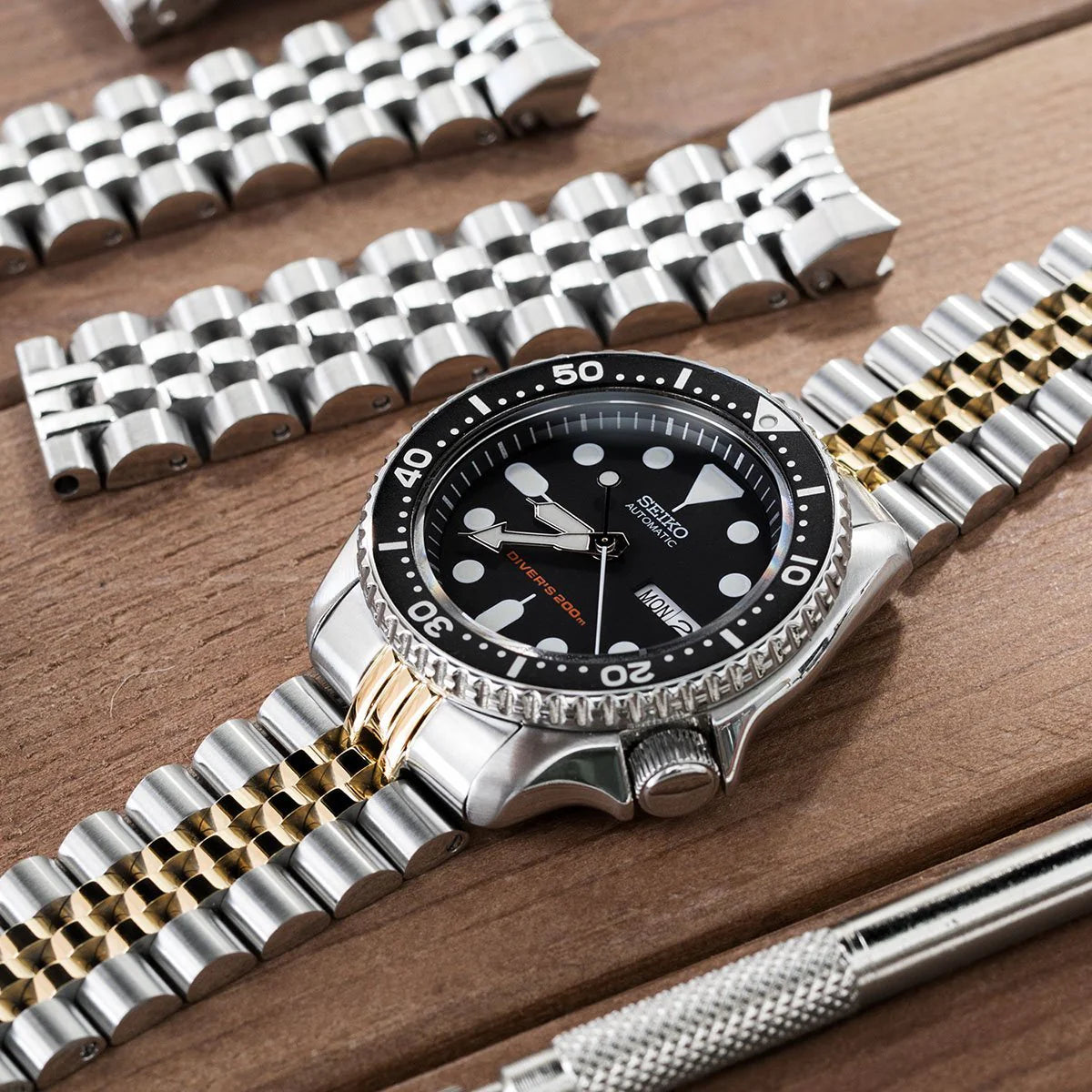 Seiko SKX007 dive watch with two-tone stainless steel and gold Super-J Louis bracelet featuring V-clasp on wooden surface