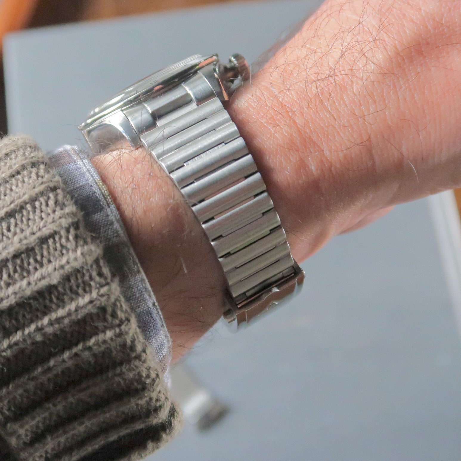 Stainless steel barrel bracelet watch worn on wrist, showing polished link construction and clasp detail