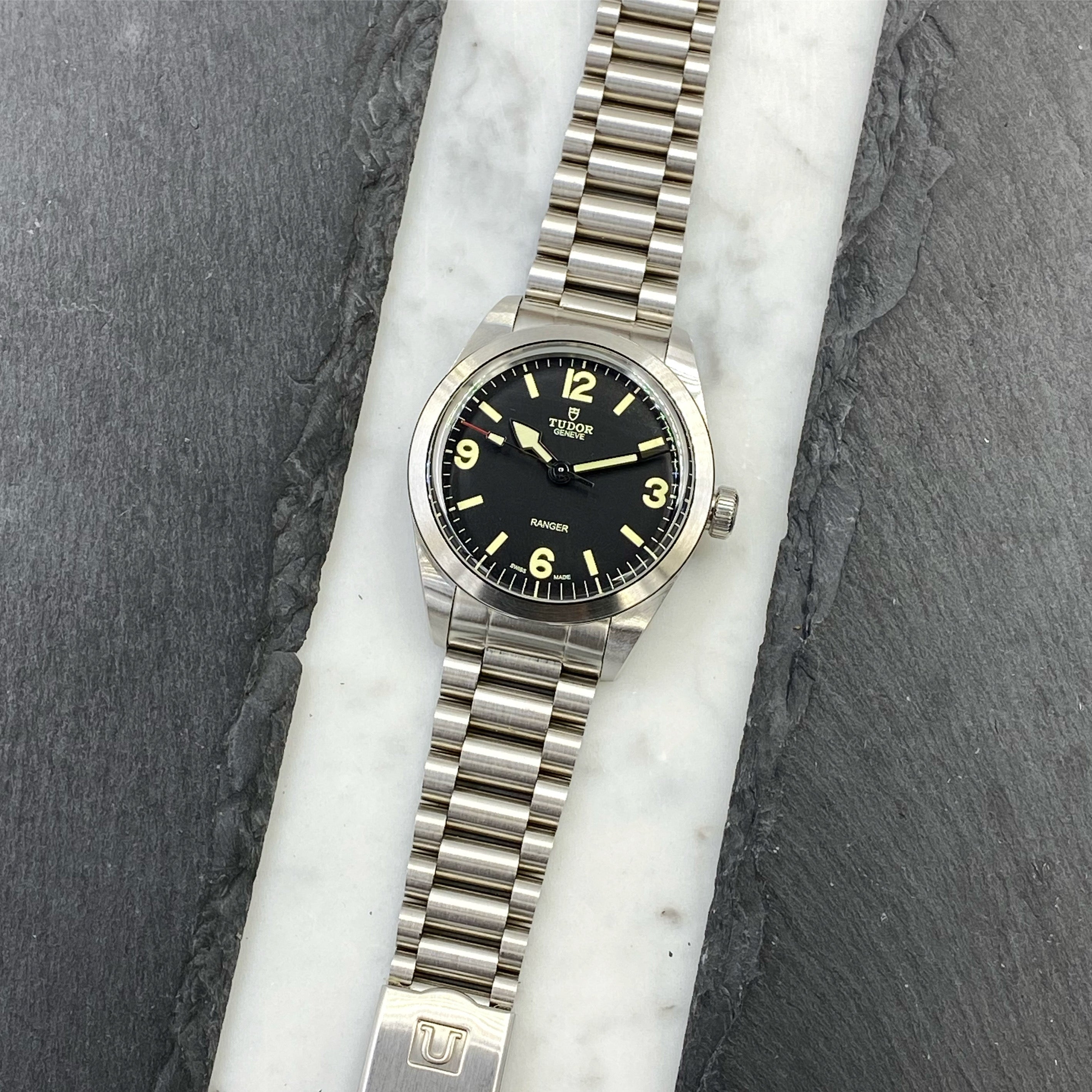 Tudor Ranger 39 watch with black dial and luminous hour markers on stainless steel bracelet, displayed on marble background