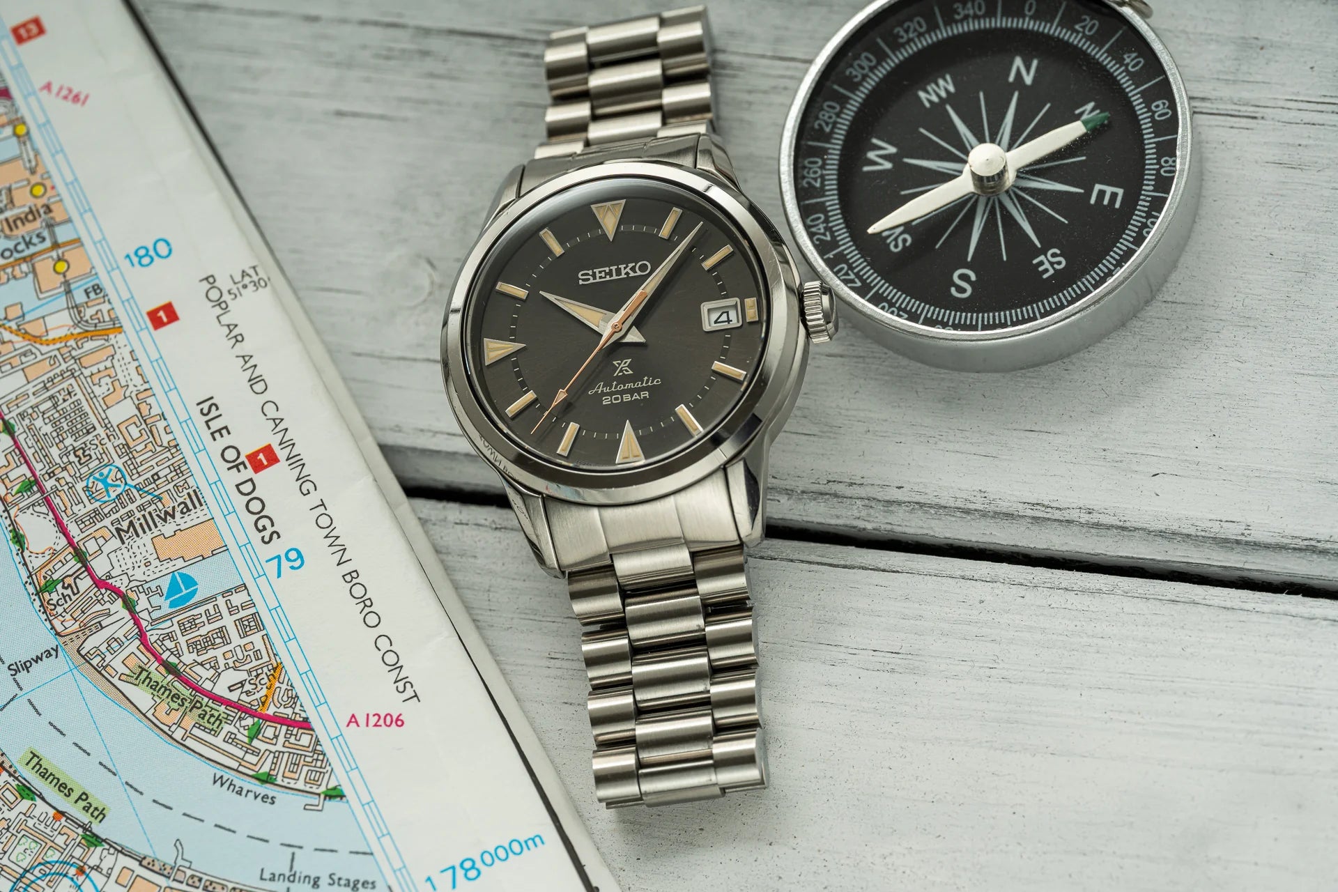 Seiko Alpinist automatic watch with steel bracelet and compass on navigation map, vintage timepiece for outdoor adventures