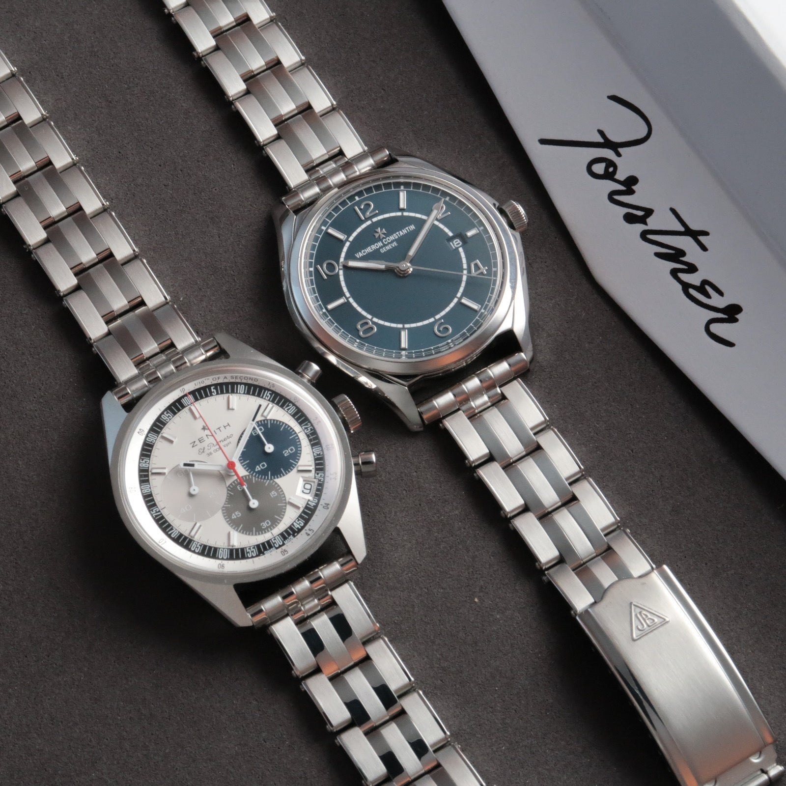 Two luxury stainless steel watches with five-link rivet bracelets on dark background next to packaging