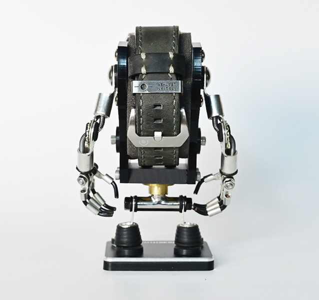 Black minibot watch stand with articulated metal arms and leather strap display, front view