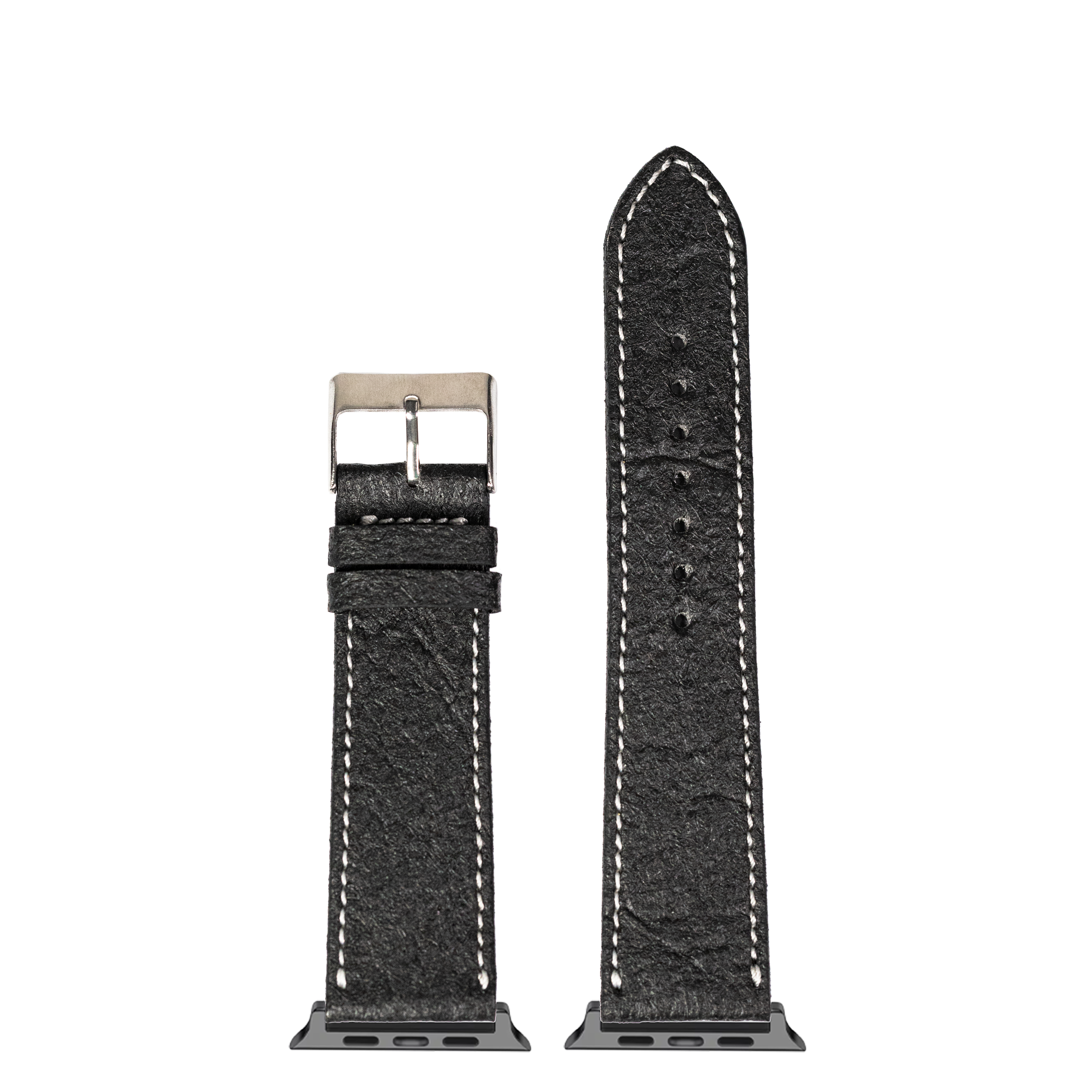 Black vegan leather Apple Watch band with white contrast stitching and stainless steel buckle, shown extended and coiled