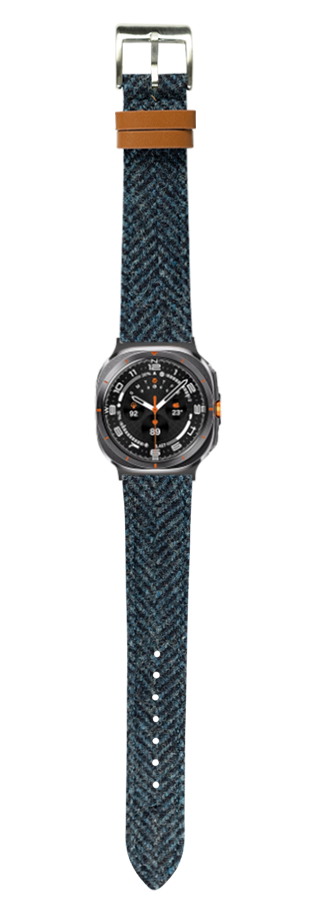 Men's sports watch with blue herringbone Harris Tweed fabric strap, brown leather trim, and black dial with orange accents
