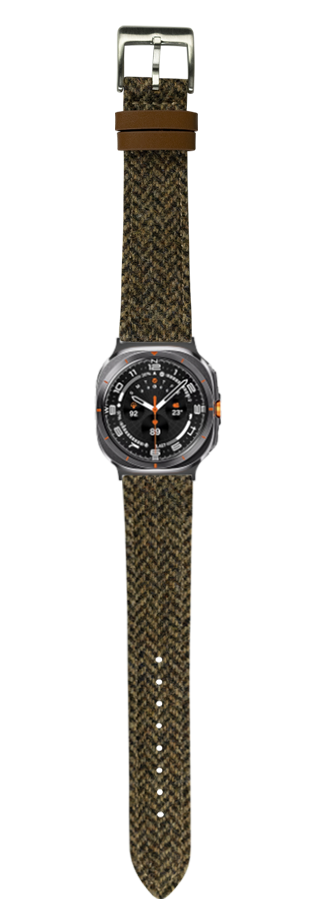 Tactical watch with dark gray case and black dial featuring orange accents, paired with olive green Harris Tweed herringbone fabric strap and brown leather keeper