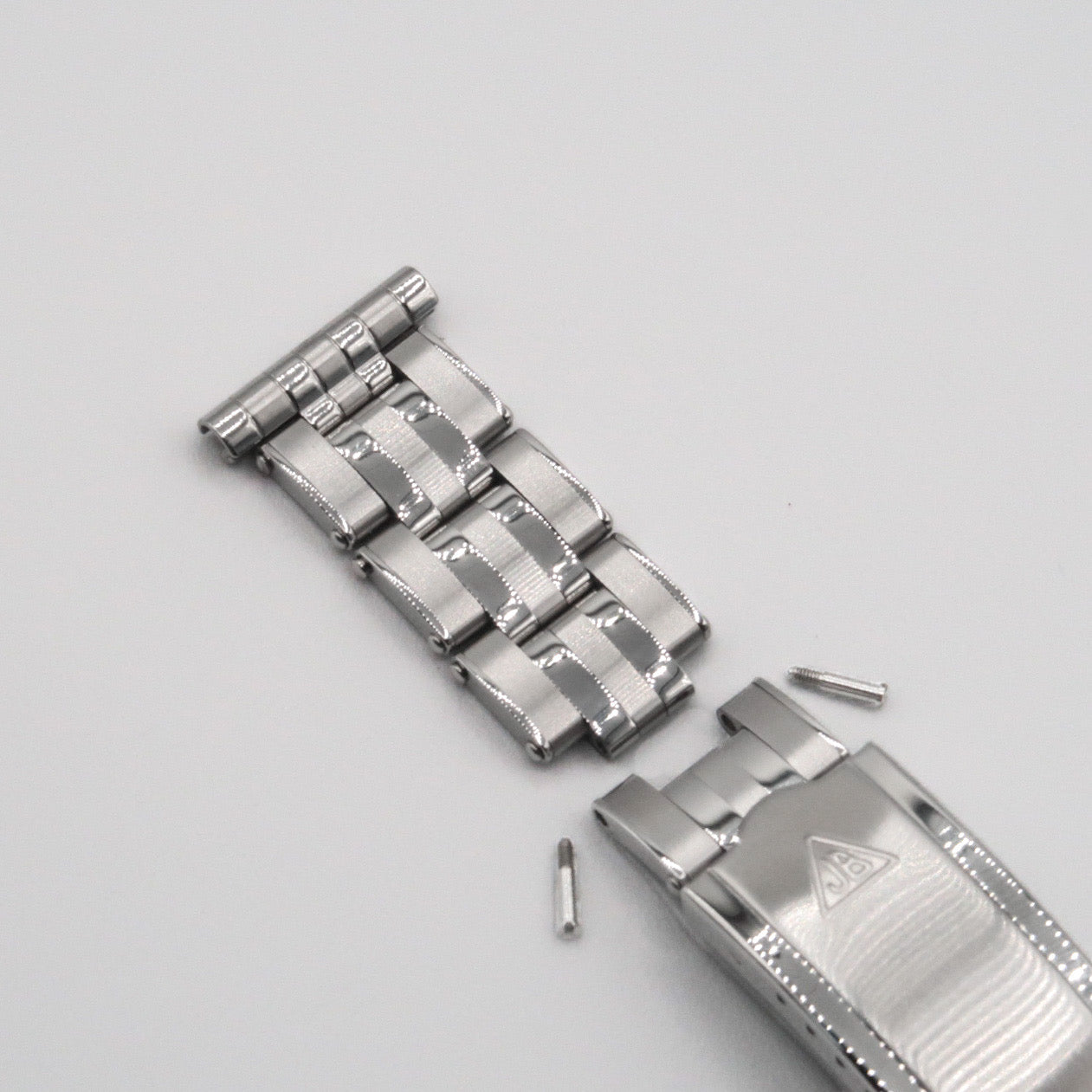 Stainless steel 5-link rivet bracelet with hinged links, pin connectors, and adjustment tools on gray background
