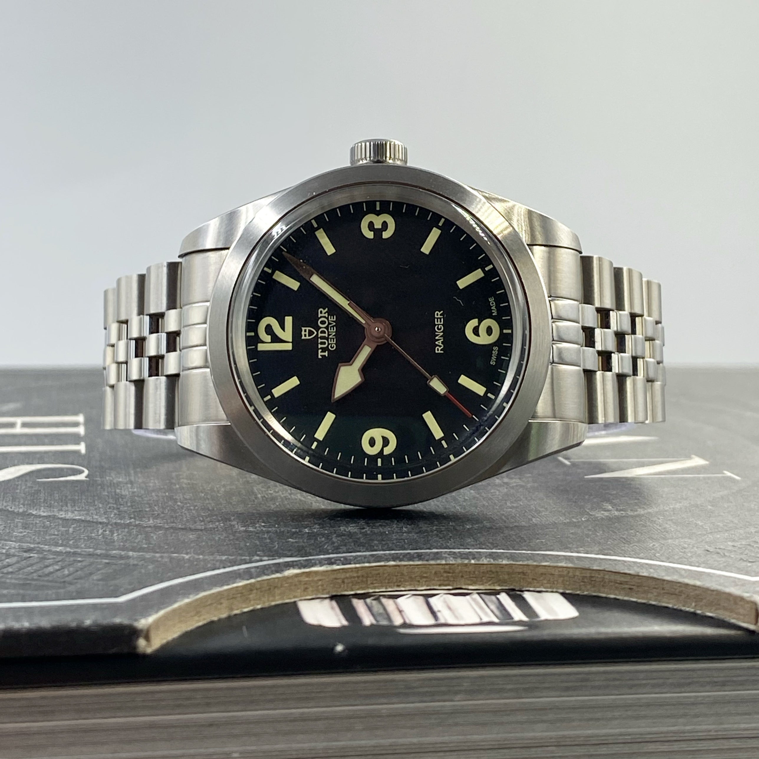 Tudor Ranger 39 stainless steel watch with black dial, luminous hour markers, and matching steel bracelet on leather display