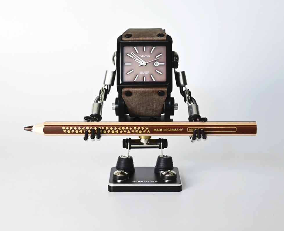Minibot black watch stand holding square-face watch with brown leather strap and decorative pencil, articulated arms and legs on black base