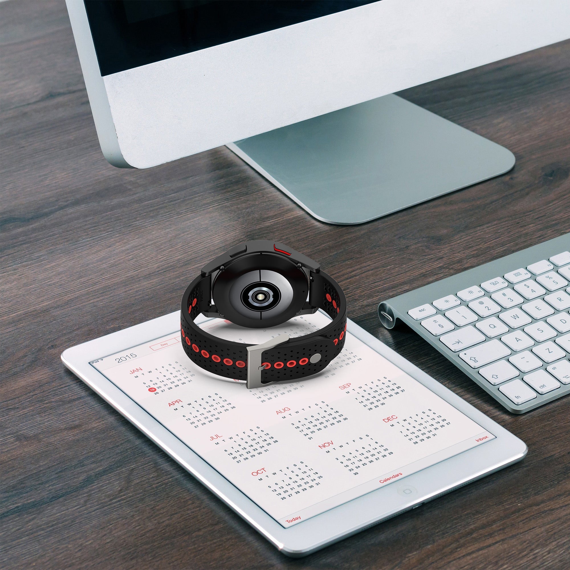 Black silicone sports watch with red accents and quick release band on desk with tablet and keyboard