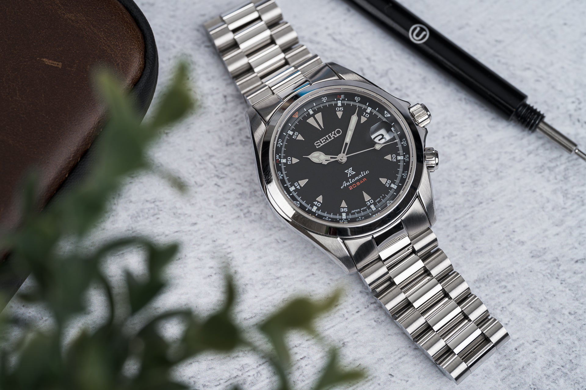 Seiko Alpinist SARB017 automatic watch with black dial and stainless steel bracelet on marble surface