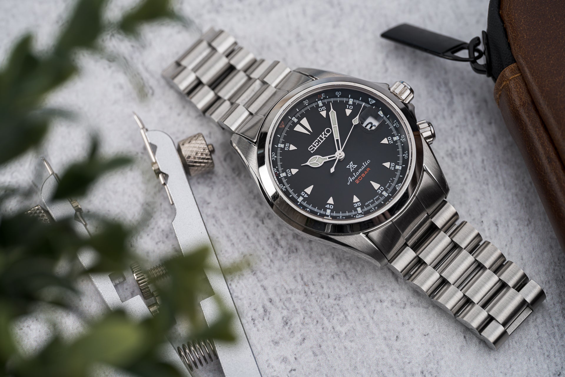 Seiko SARB017 Alpinist stainless steel watch with black dial and metal bracelet on gray surface