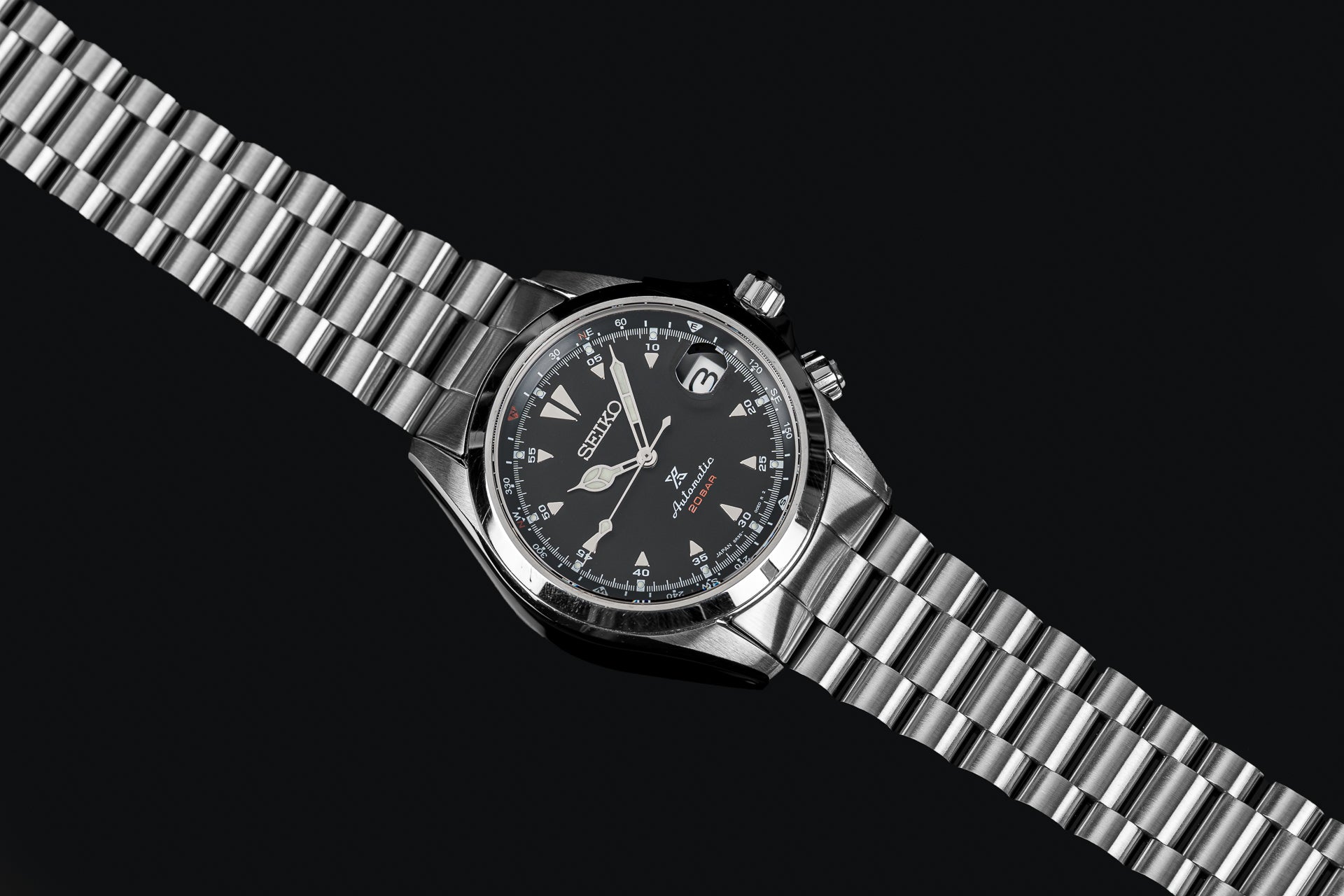 Seiko SARB017 Alpinist stainless steel watch with black dial, date window, and metal bracelet on black background