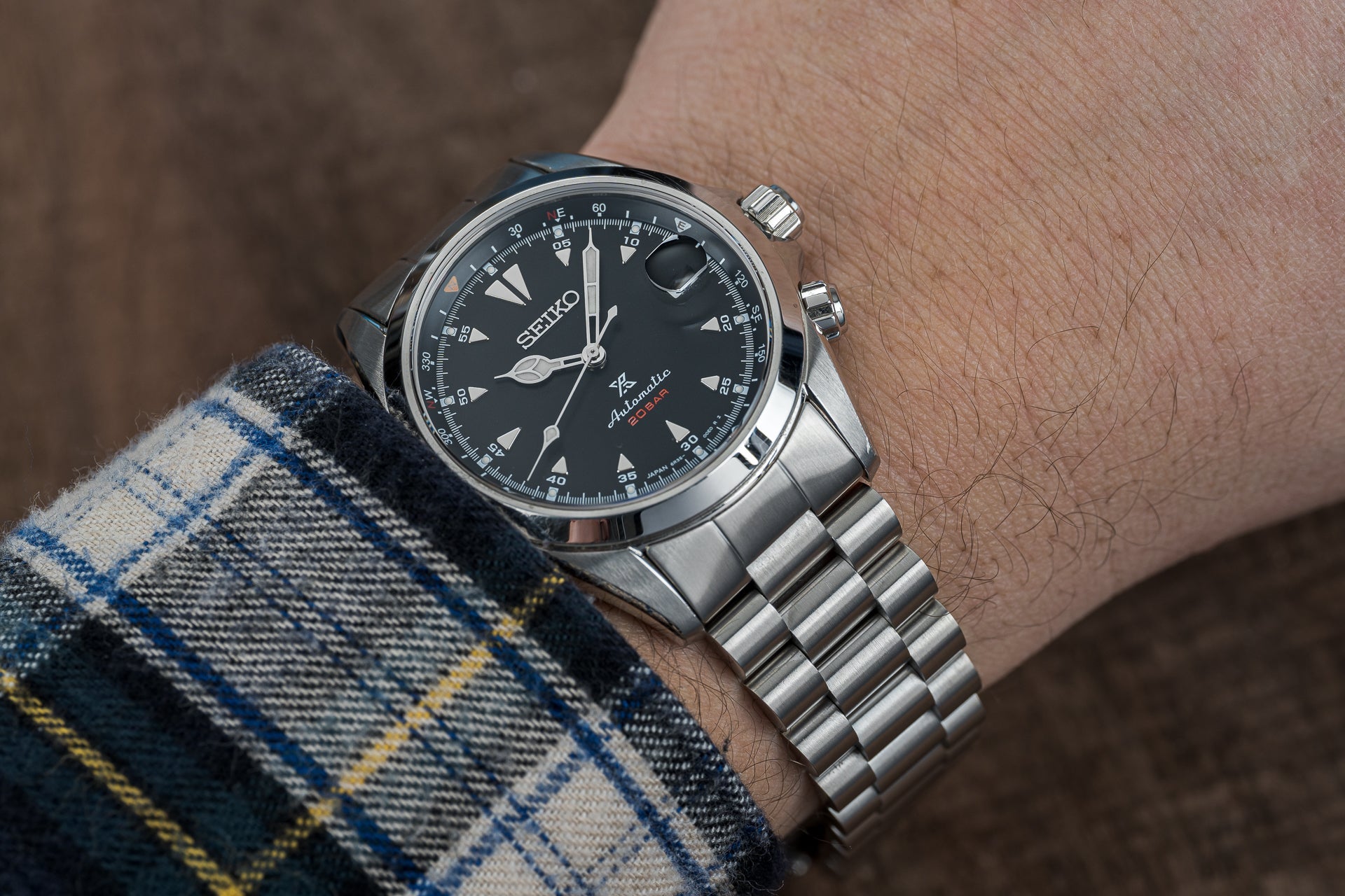 Seiko Prospex SARB017 automatic watch with black dial, stainless steel bracelet, worn on wrist with plaid sleeve