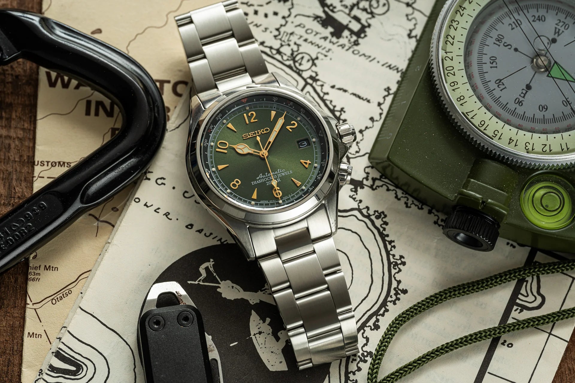 Seiko Prospex automatic watch with green dial and steel bracelet displayed with compass and tactical gear on vintage map