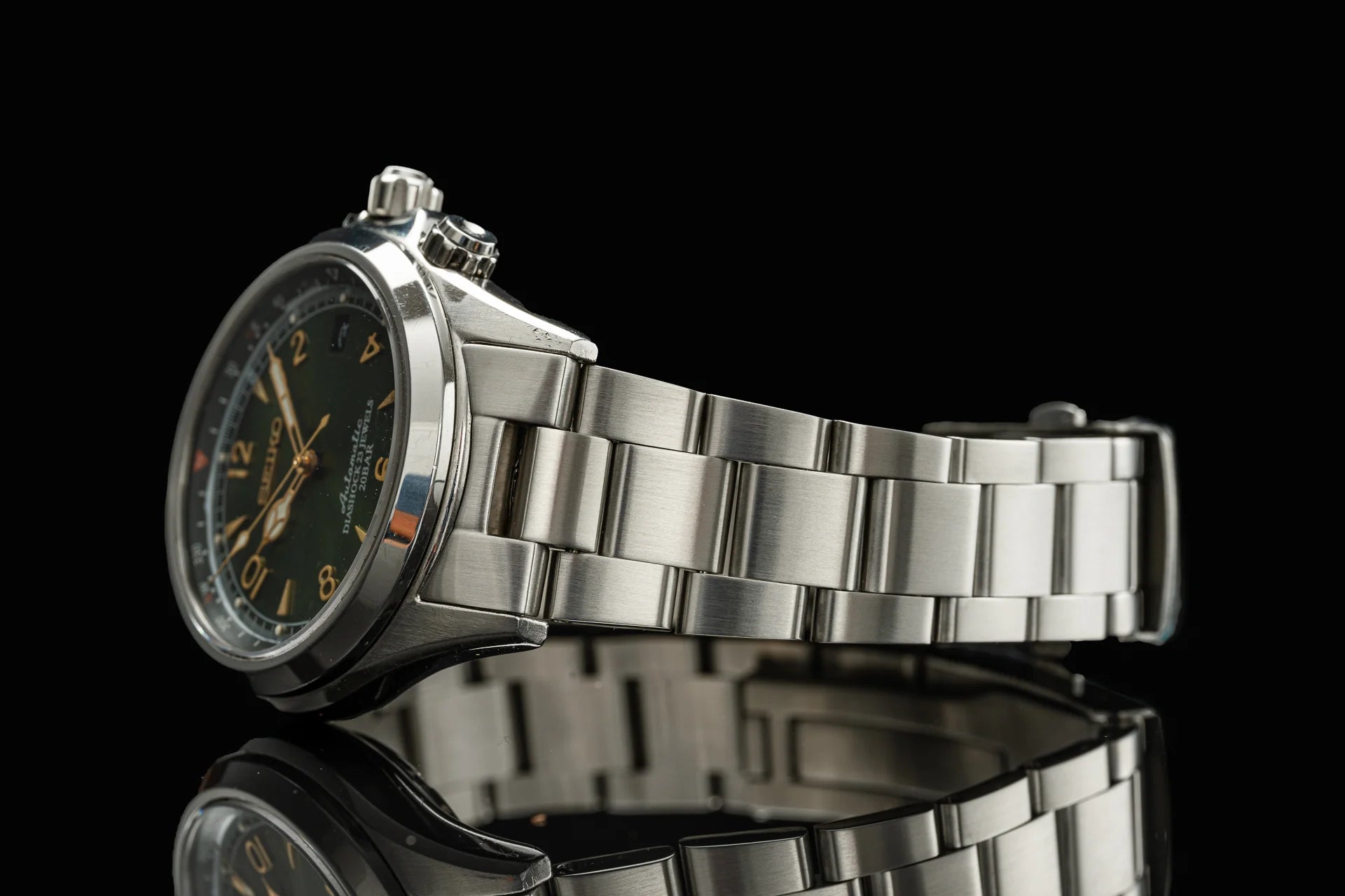Seiko SARB017 Senator automatic watch with dark dial, golden numerals and hands, stainless steel bracelet on black background