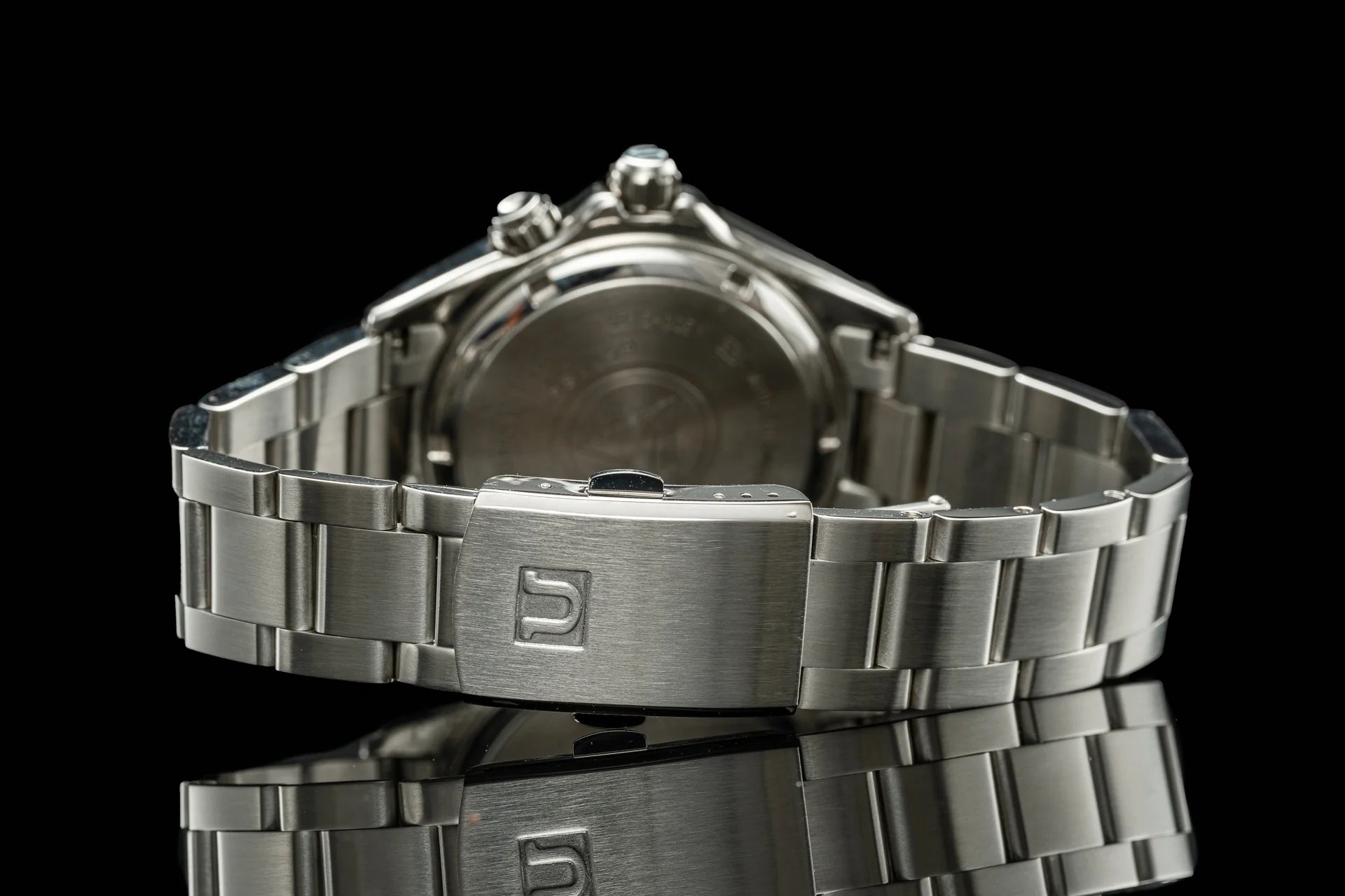 Stainless steel chronograph watch with metal bracelet and fold-over clasp, back case view on black background
