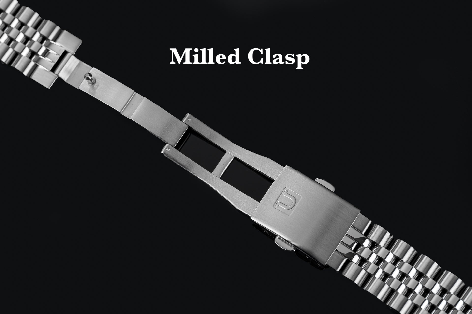 Stainless steel milled clasp watch bracelet with solid end links and deployment buckle on black background