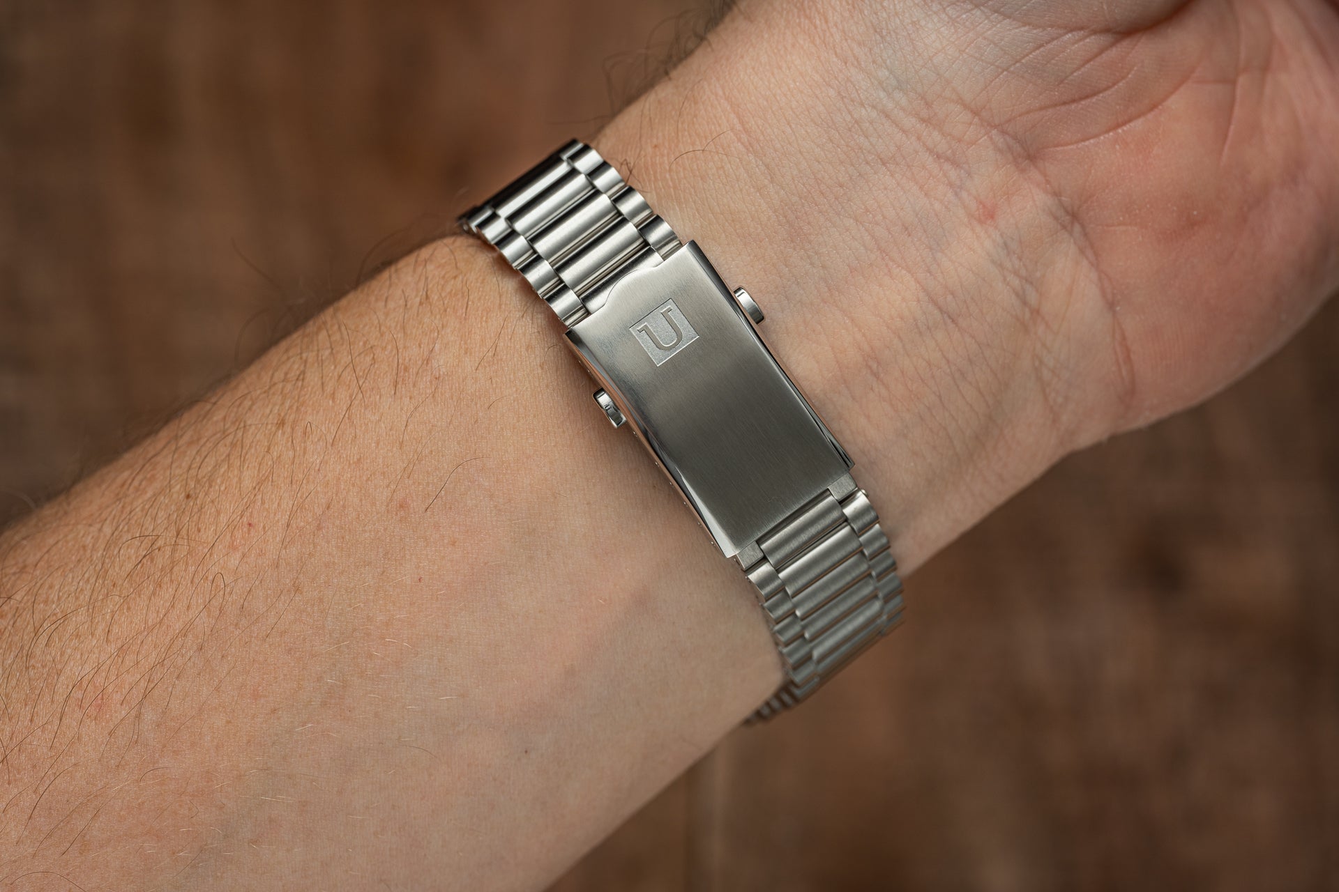 Stainless steel watch bracelet with polished links and brushed center clasp on man's wrist