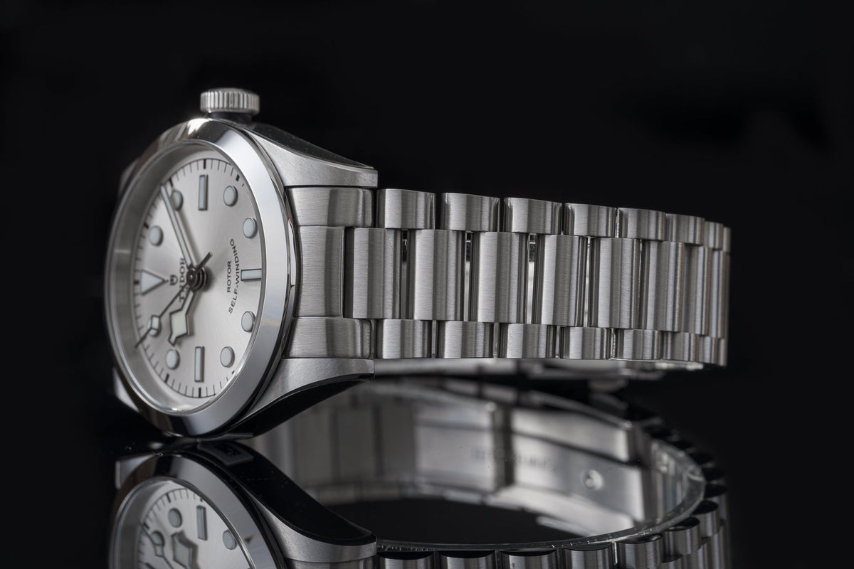Silver stainless steel bracelet watch with white dial and link band on black background