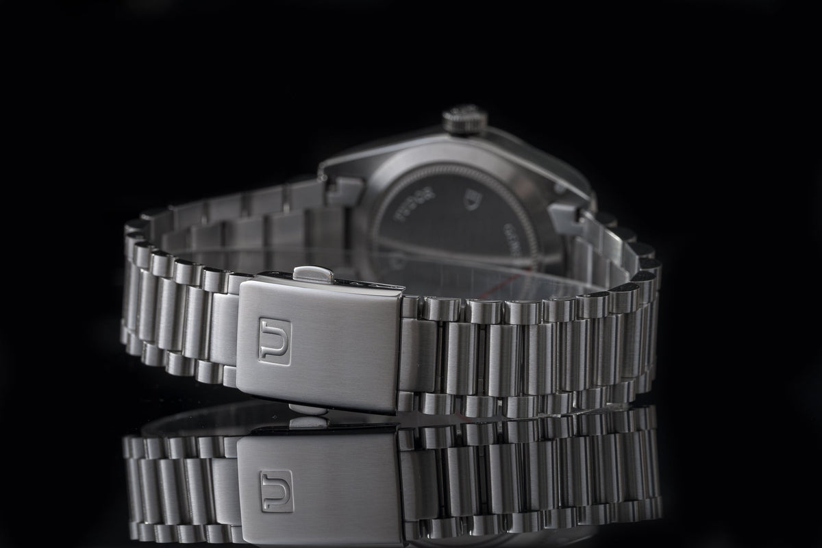 Stainless steel bracelet with brushed clasp for Tudor Black Bay 36 watch on black background