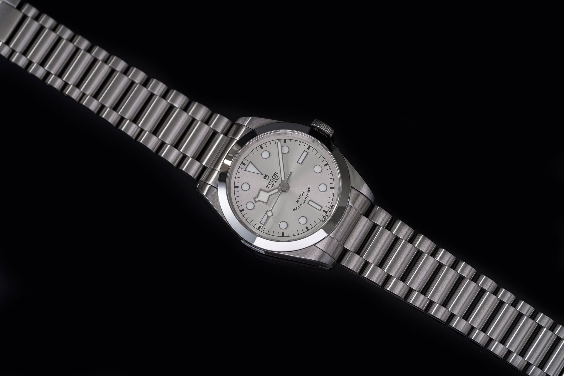 Stainless steel bracelet watch with silver dial, round case, and link band against black background