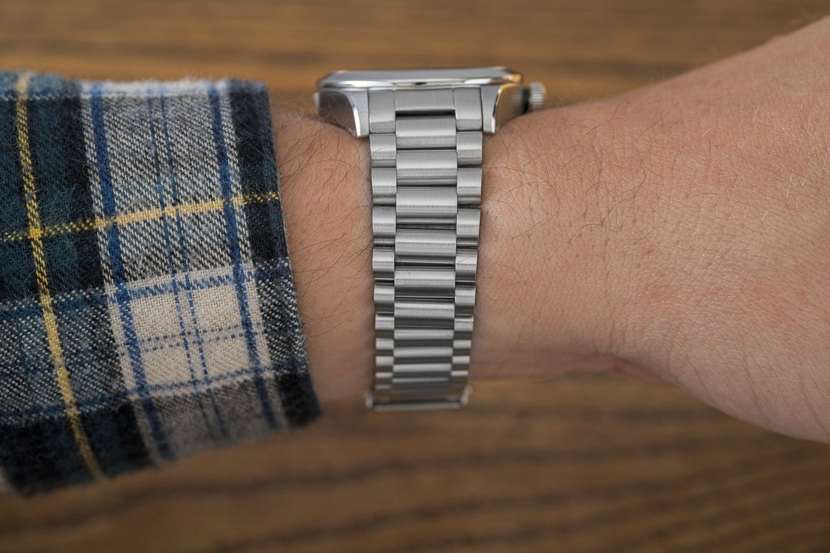 Stainless steel three-link bracelet worn on wrist with plaid shirt cuff, compatible with Tudor Black Bay 36 watch