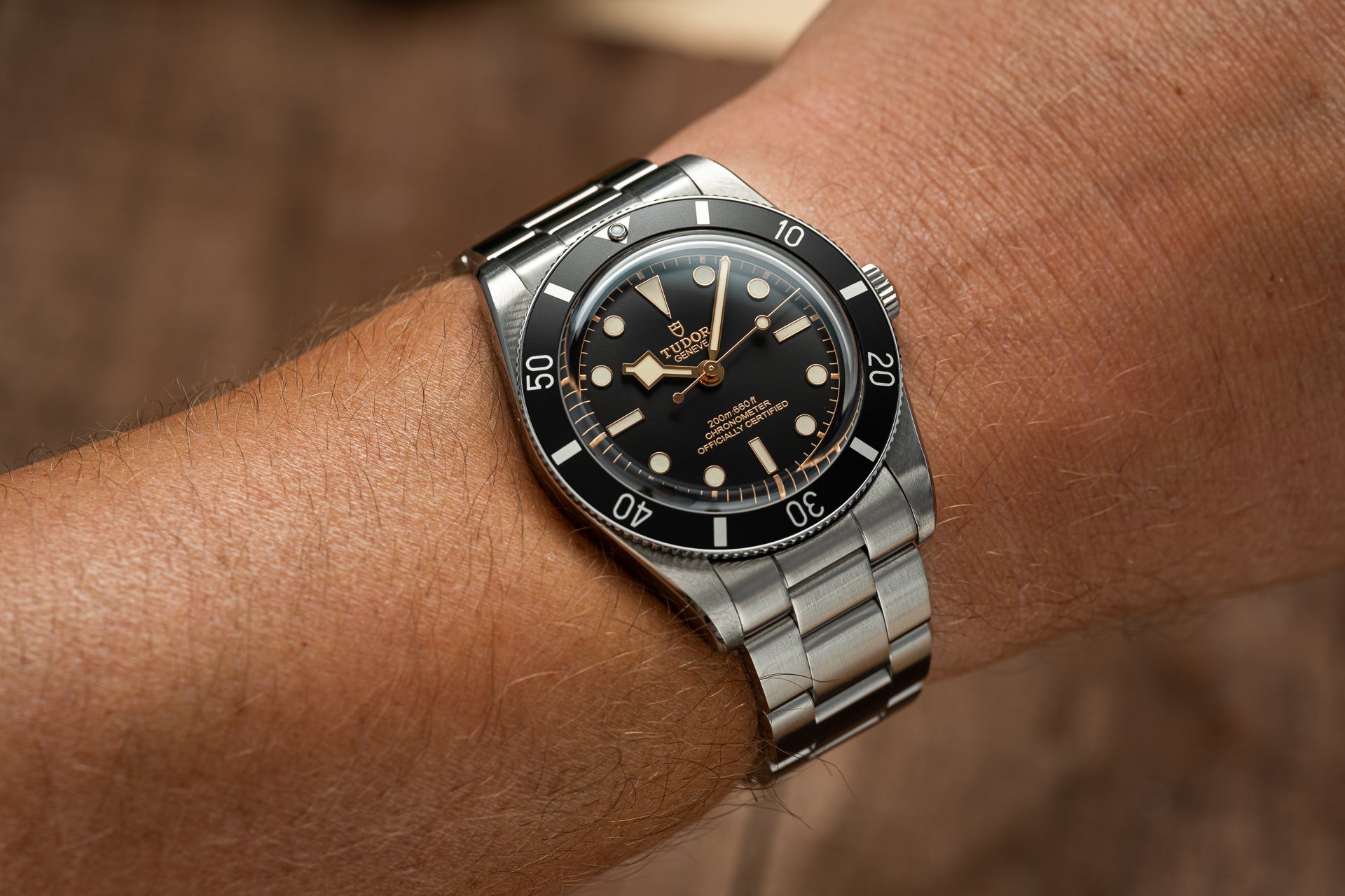 Stainless steel dive watch with black dial and bezel on wrist, showing metal bracelet and luminous hour markers