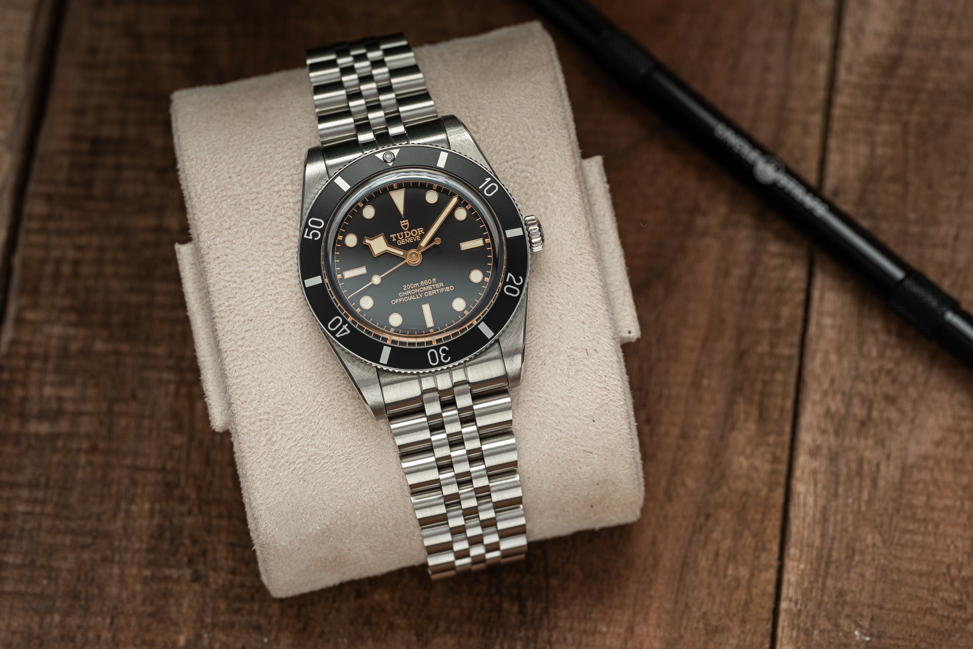Tudor Black Bay 54 stainless steel dive watch with black bezel and gilt dial on jubilee bracelet displayed on watch pillow