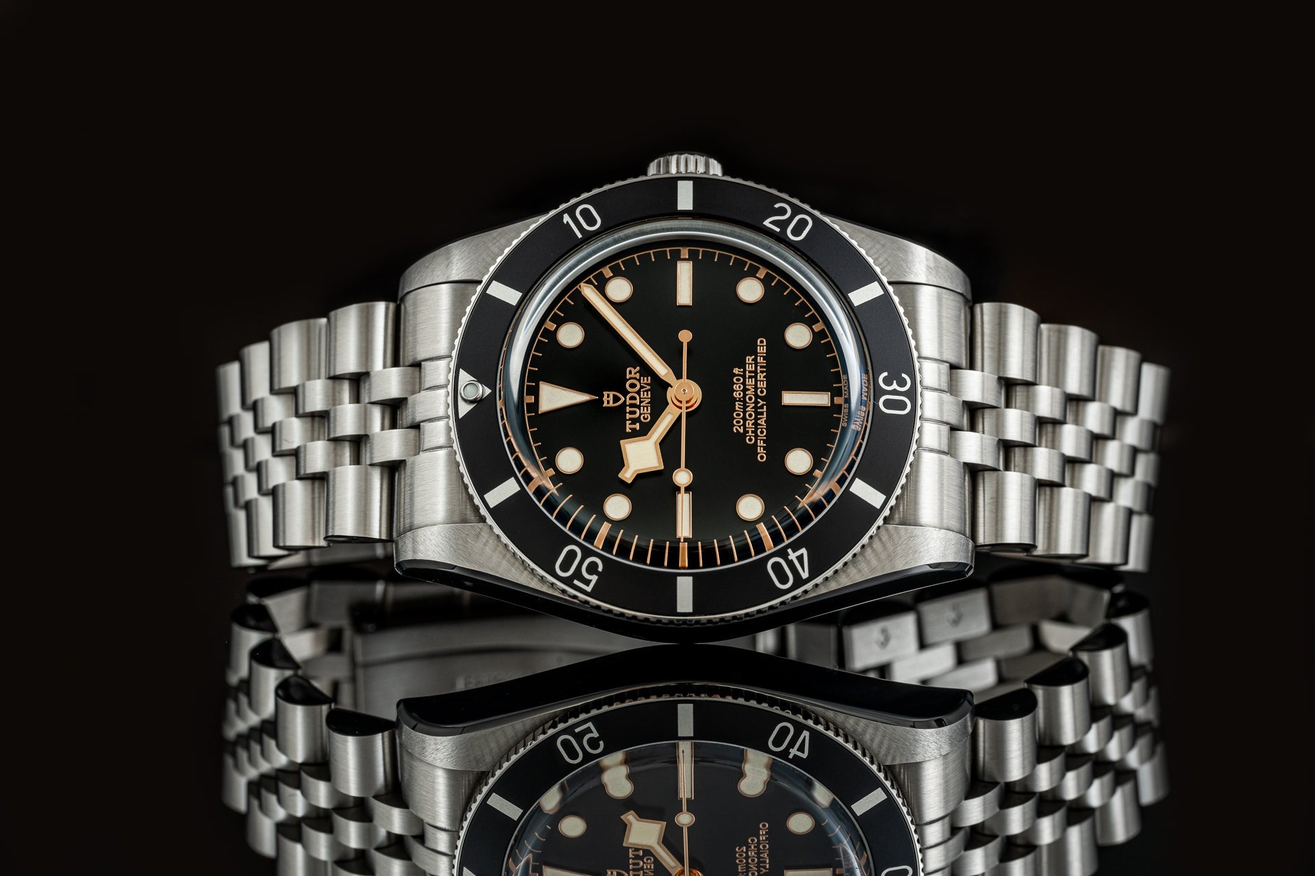 Tudor Black Bay 54 luxury dive watch with stainless steel bracelet, black dial, and rose gold hands on black background