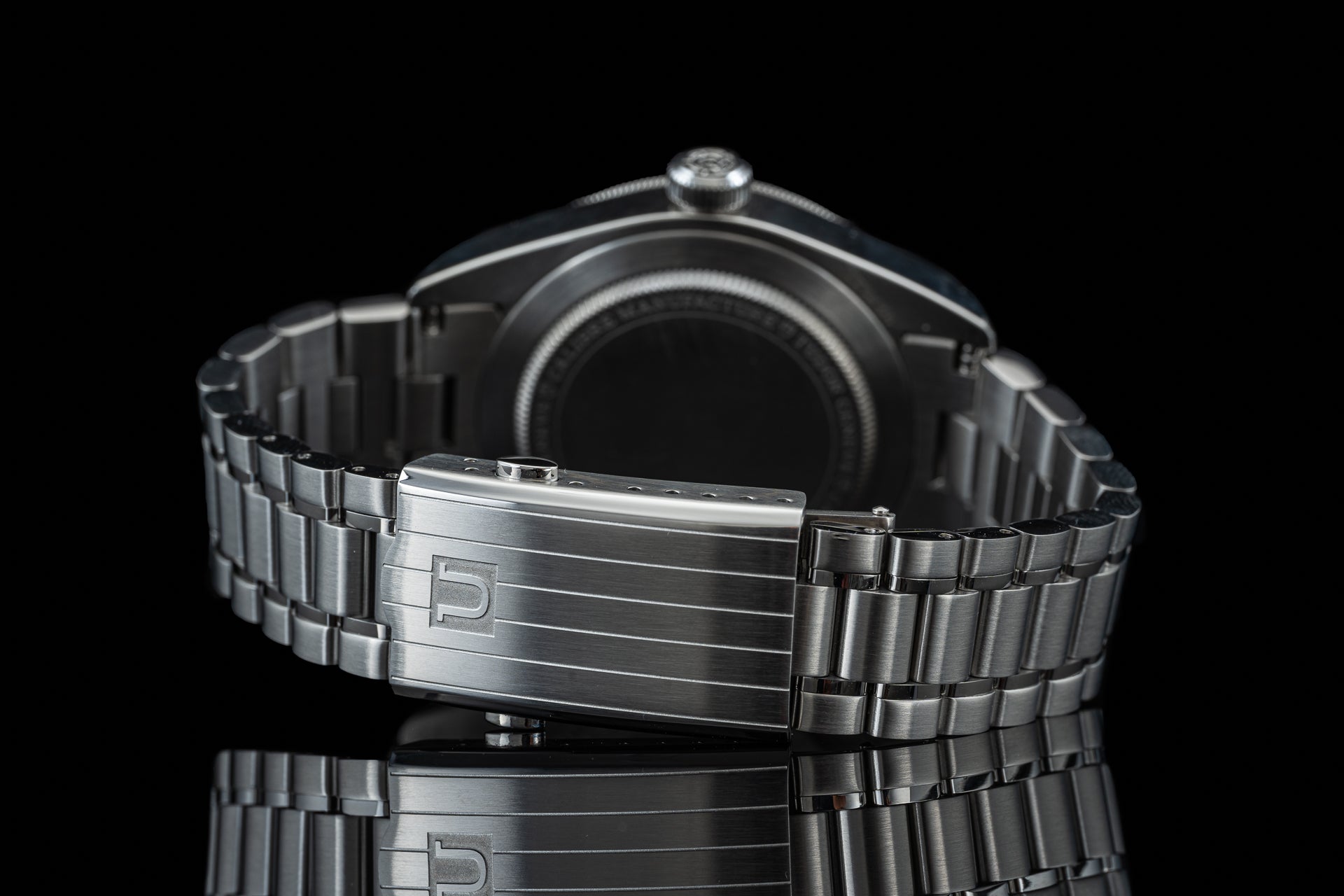 Stainless steel three-link bracelet with fold-over clasp for Tudor Black Bay 58 watch, side view on black background