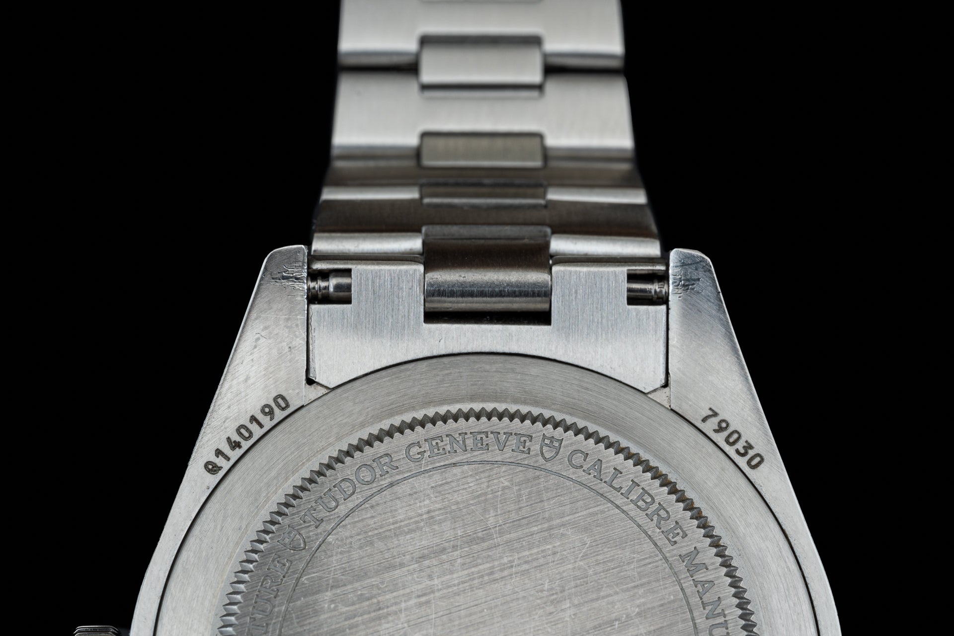 Stainless steel watch bracelet with solid link construction and end links, showing back case marking and serial numbers